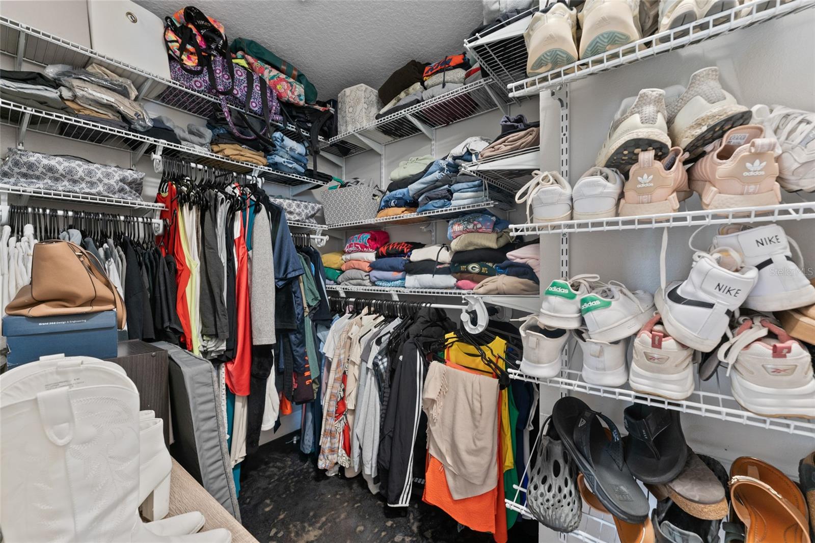 This spacious walk-in closet offers ample storage with custom wire shelving and organization space for clothes, shoes, and accessories. Closet goals achieved!