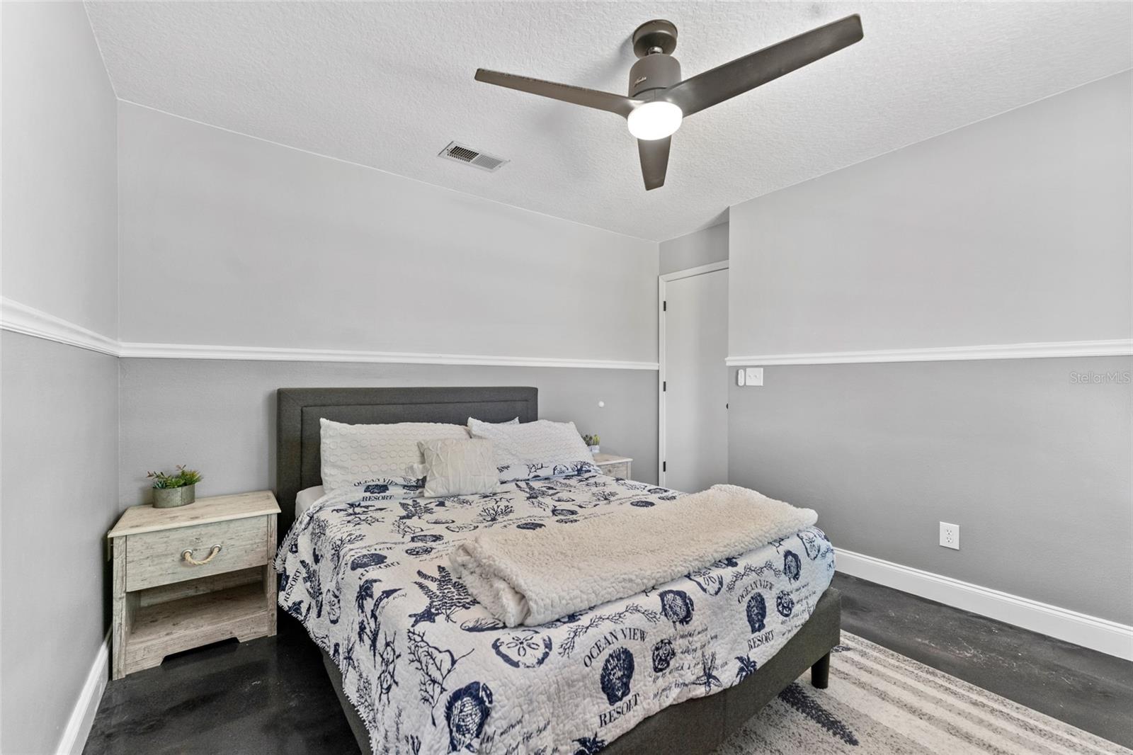 Perfect for guests or family, this second bedroom features calming gray tones, a modern fan, and clean trim work for a fresh, move-in ready feel.