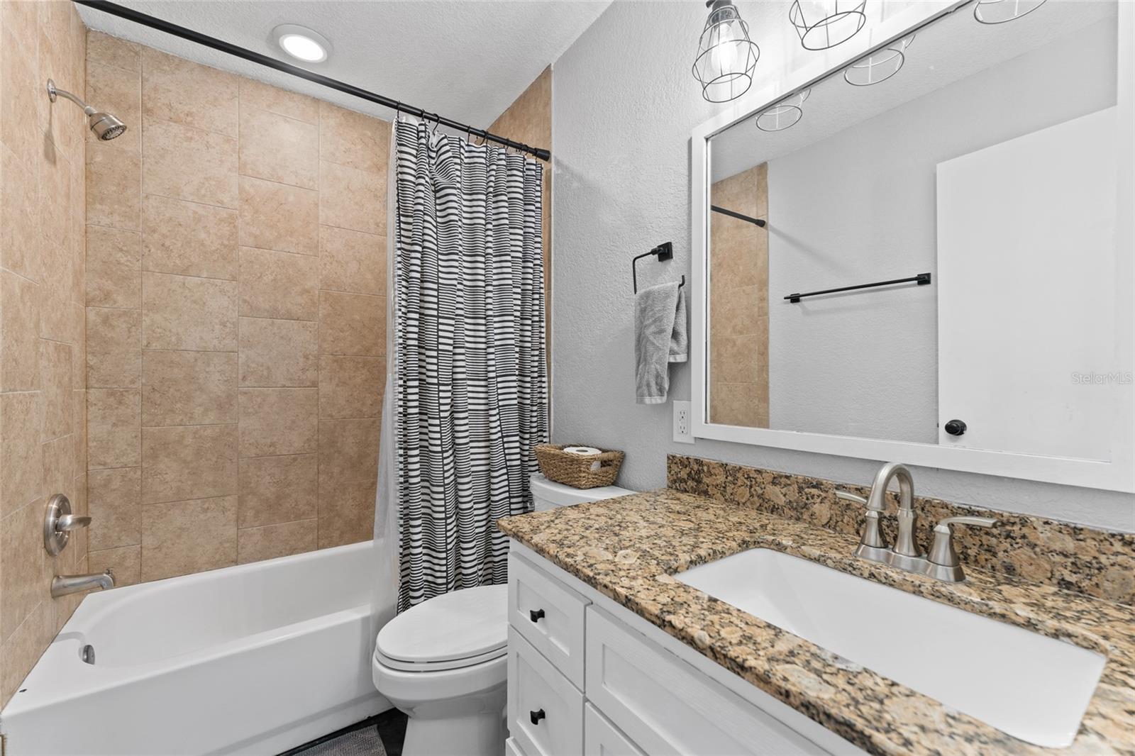 This guest bath is both functional and stylish with granite countertops, a modern vanity, and a tiled tub/shower combo—perfect for everyday use or hosting visitors.