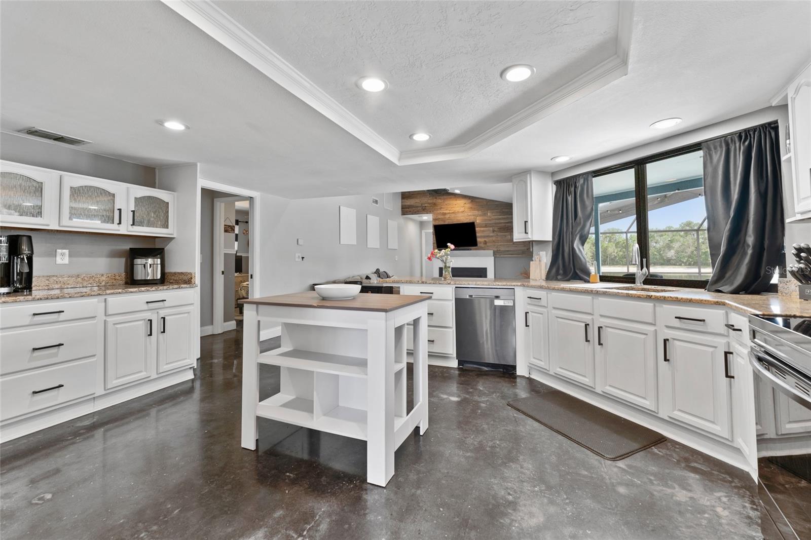 A dream kitchen awaits with granite countertops, stainless steel appliances, white shaker cabinetry, and a central island perfect for meal prep or morning coffee. Move-in ready in Tampa's desirable community!