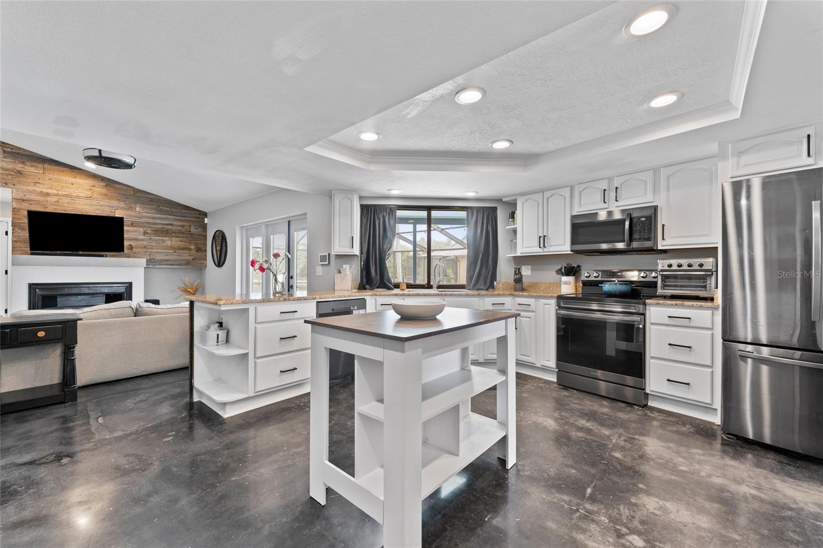 This open-concept kitchen is both functional and beautiful with recessed lighting, expansive counters, and sleek black fixtures. Entertain with ease from the heart of the home.