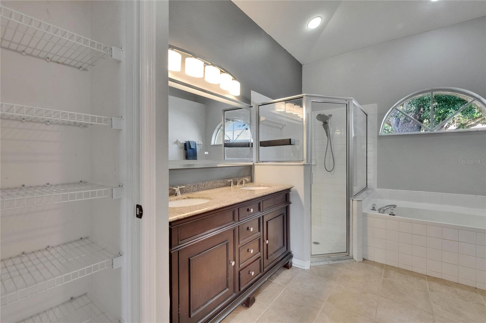 Linen closet, dual vanity, shower and tub combo in primary bathroom.