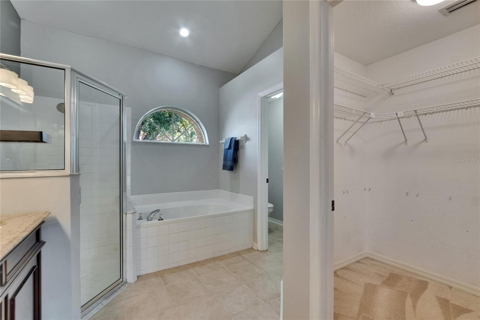 Shower and tub combo, "throne room" and walk in closet in primary bathroom.