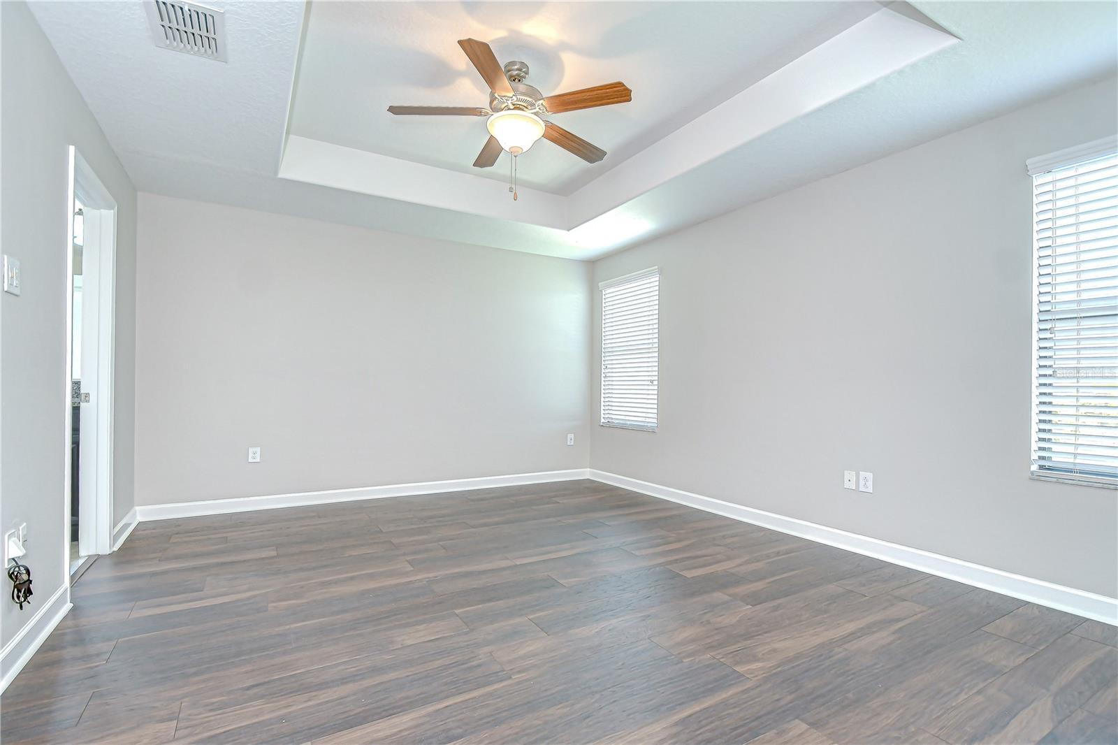 Primary suite is stunning with wood flooring and tray ceiling!