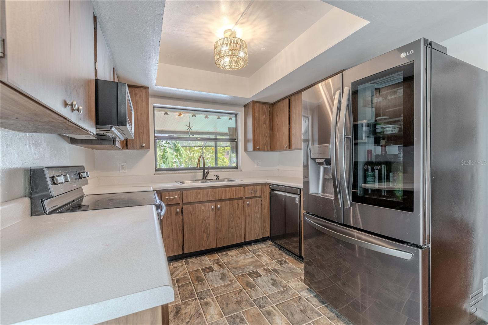 A tray ceiling with contemporary lighting adds visual interest, while the adjacent open floor plan keeps the kitchen connected to the family and dining areas.