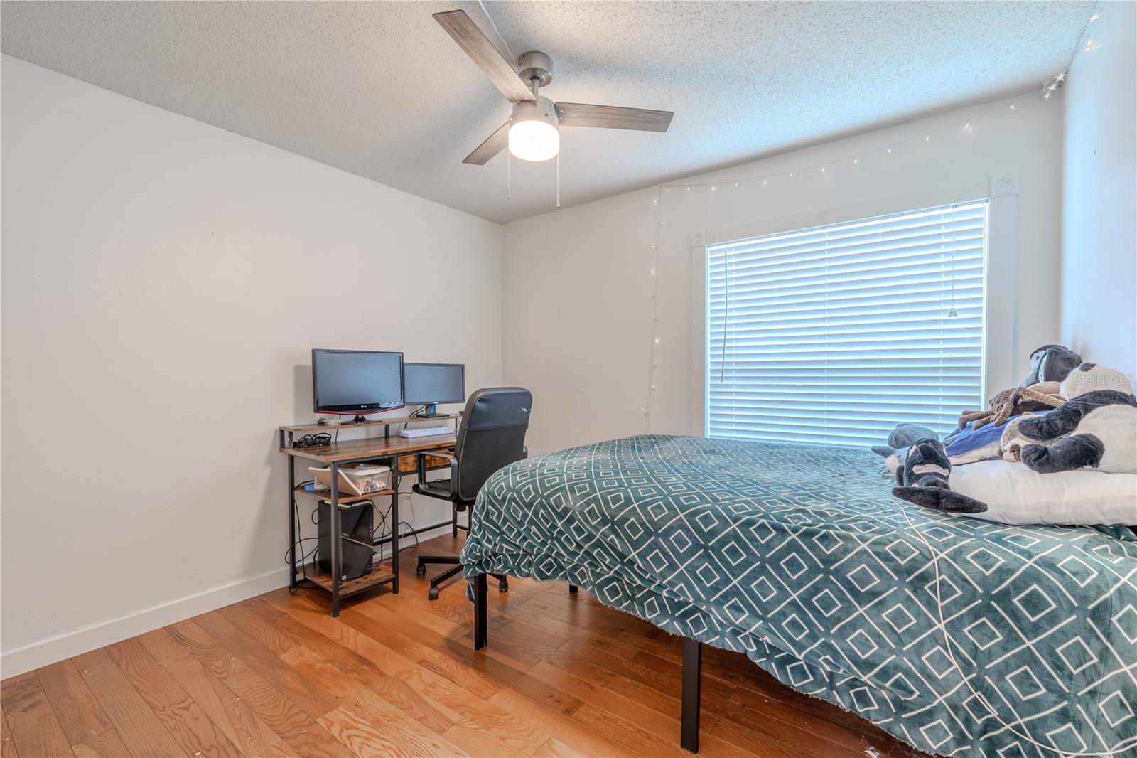Bedroom 3 features neutral tones,  hardwood floor, a ceiling fan and built-in closet.