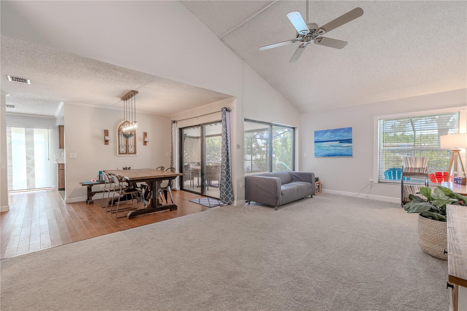 Spacious dining area with hardwood floors direct access to the screened lanai and pool through large sliding glass doors, creating a seamless indoor-outdoor flow. A modern light fixture adds character and illuminates the space, while the open sightlines to the living room and kitchen enhance the home’s open-concept feel. This inviting space comfortably accommodates a large dining table and provides a relaxed yet functional setting for gathering.