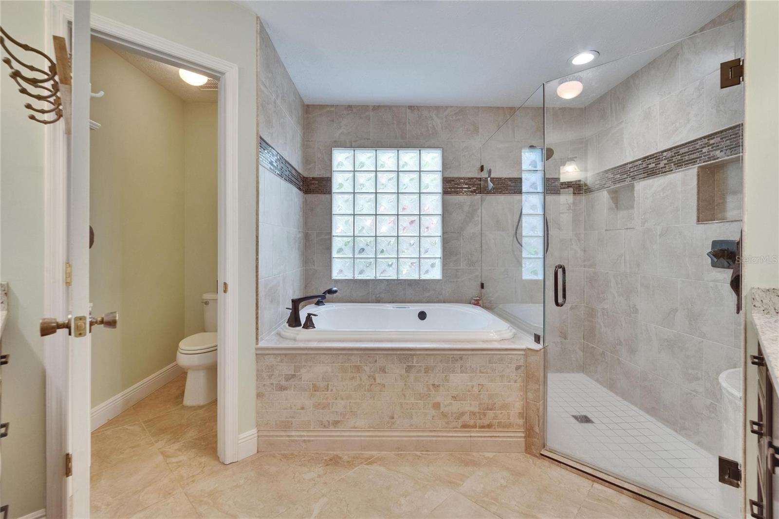 Beautifully remodeled primary bath jacuzzi tub and tiled shower.