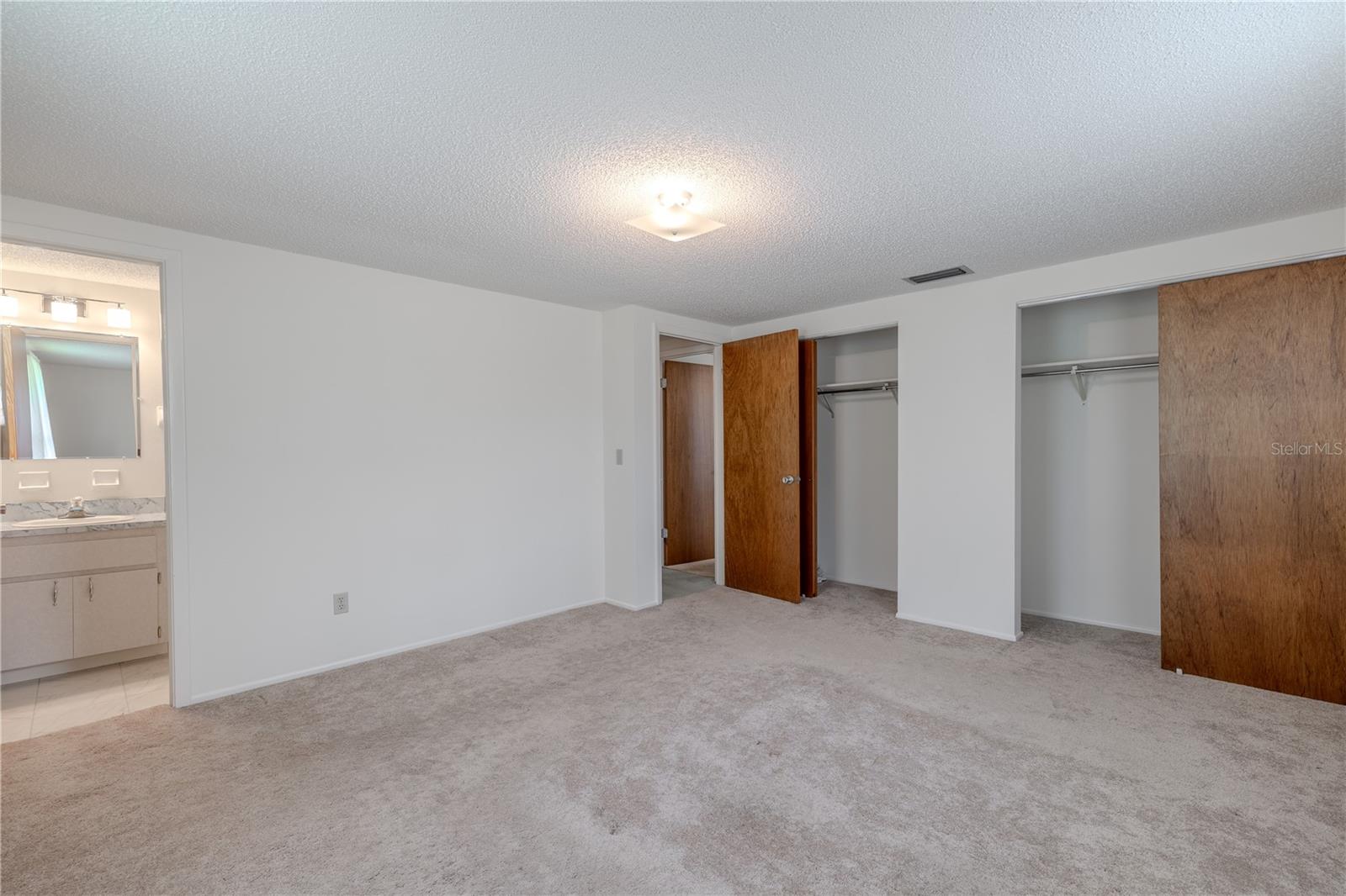 Bedroom #2 is spacious and filled with natural light from two large windows, creating a warm and inviting atmosphere. Neutral carpeting and walls provide a blank canvas ready for any décor style. This room includes dual closets for generous storage and direct access to a private en suite bathroom—making it an ideal setup for guests, a teen suite, or multi-generational living. With its practical layout and peaceful vibe, this bedroom offers both comfort and flexibility.