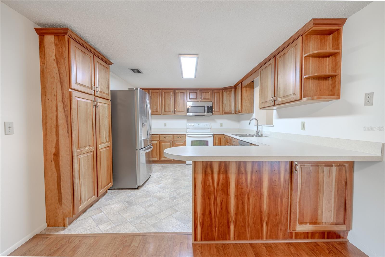 The kitchen is equipped with ample cabinetry, a full appliance suite, and a convenient wraparound breakfast bar that provides extra seating or serving space. Whether you're relaxing or entertaining, this layout is designed for comfort and convenience.