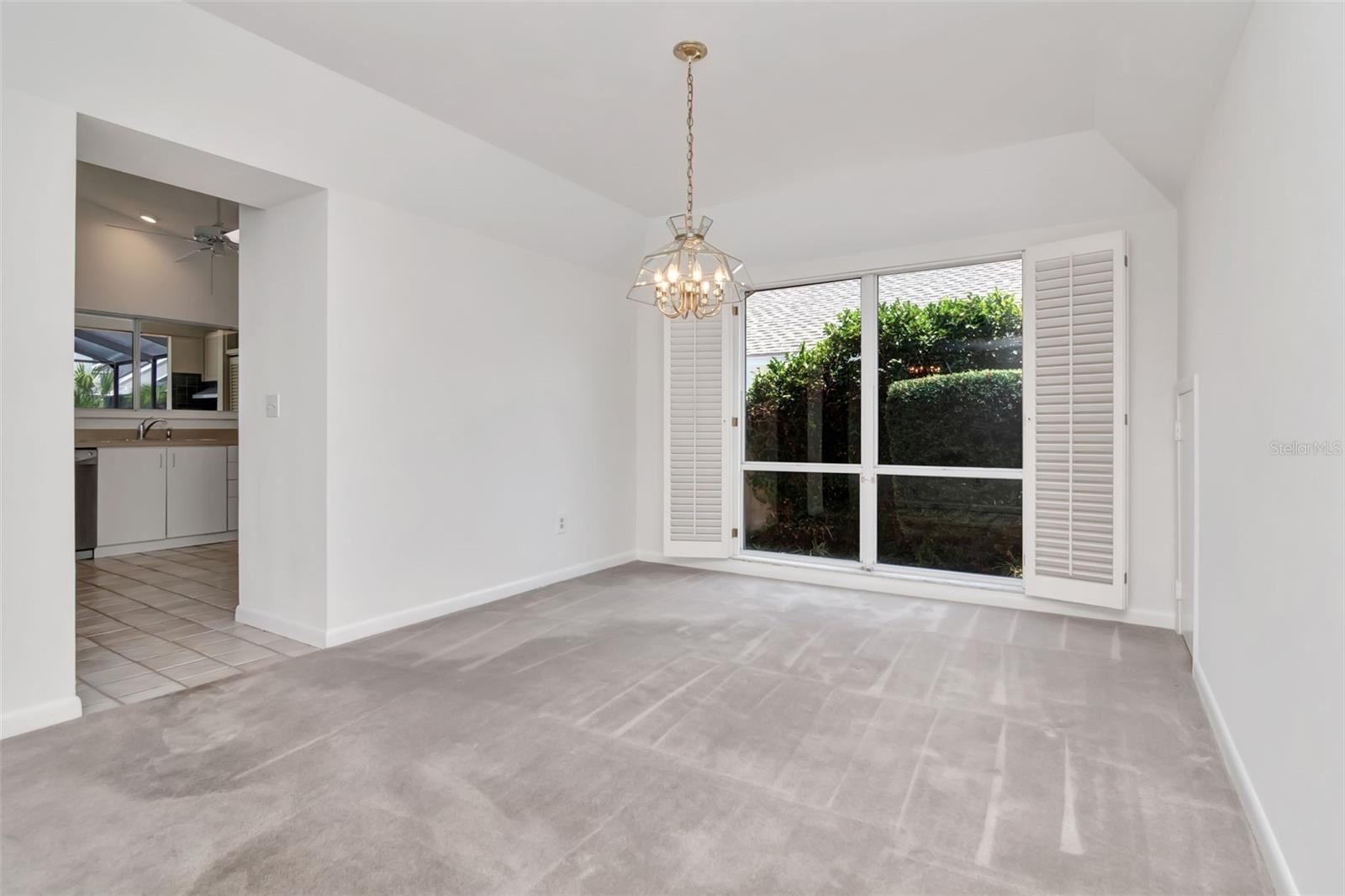 Dining room with high ceilings is just off the kitchen and overlooks green space of side yard and vine covered wall along property line allowing the light but providing privacy.