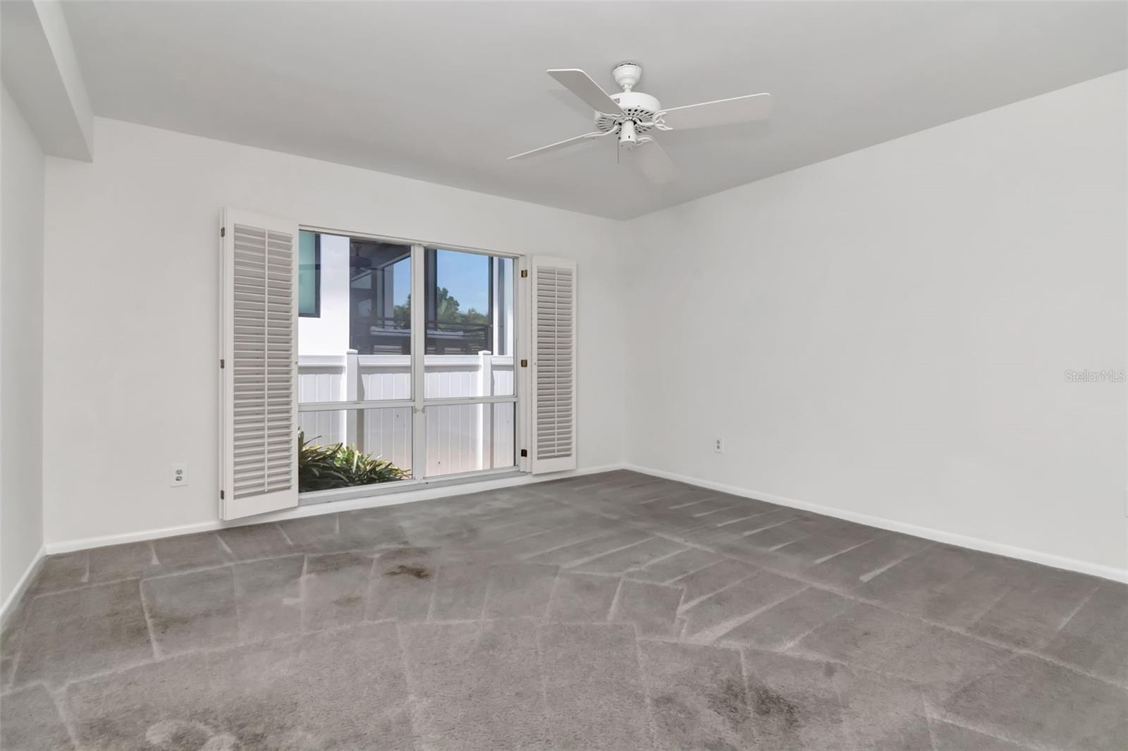 Primary bedroom with double windows and interior shutters.