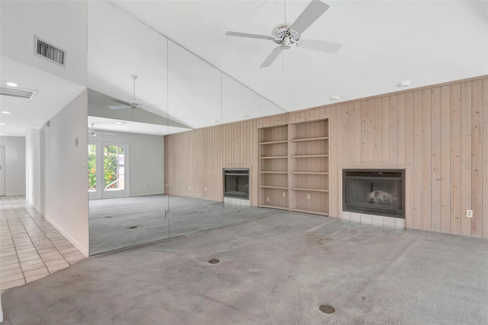 Soaring ceilings, fireplace, pickled paneling and a wall of mirrors create a light family room open to the kitchen and overlooking the pool.