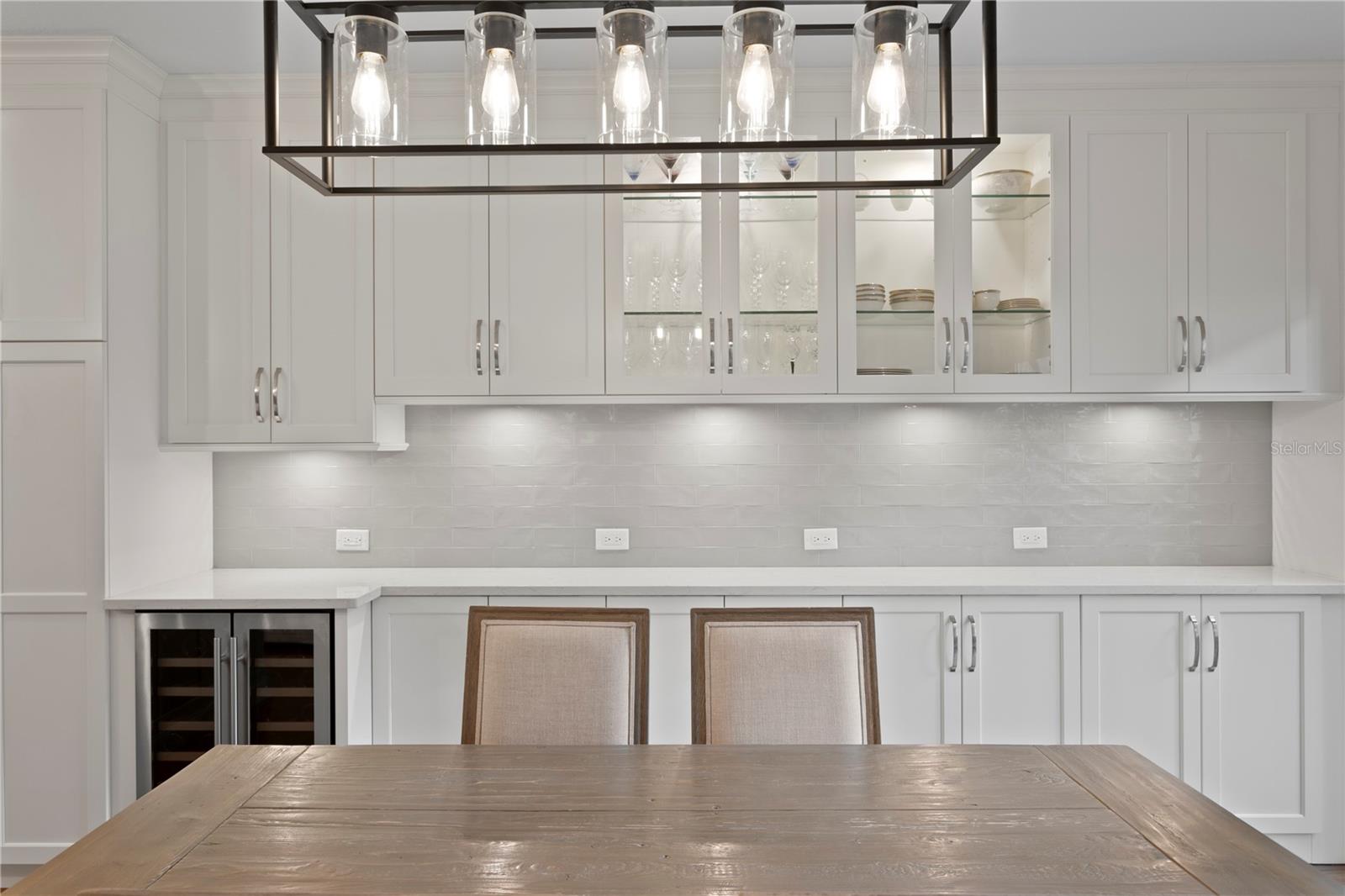 This gorgeous kitchen/dining space features beautiful light fixtures, glass front cabinet doors and a tremendous amount of counter space!
