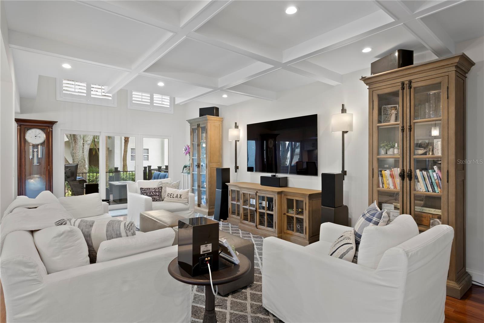 Coffered ceilings add architectural charm to this sunlit living space that is open to the kitchen, keeping everyone connected.