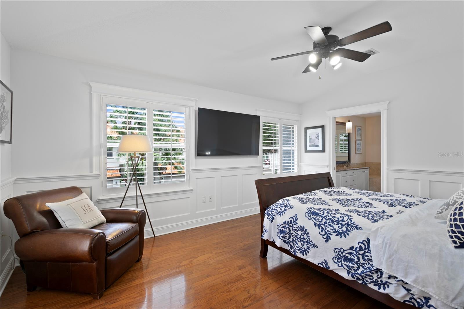 The spacious primary bedroom features gleaming hardwood floors, plantation shutters, and room for a cozy reading nook.