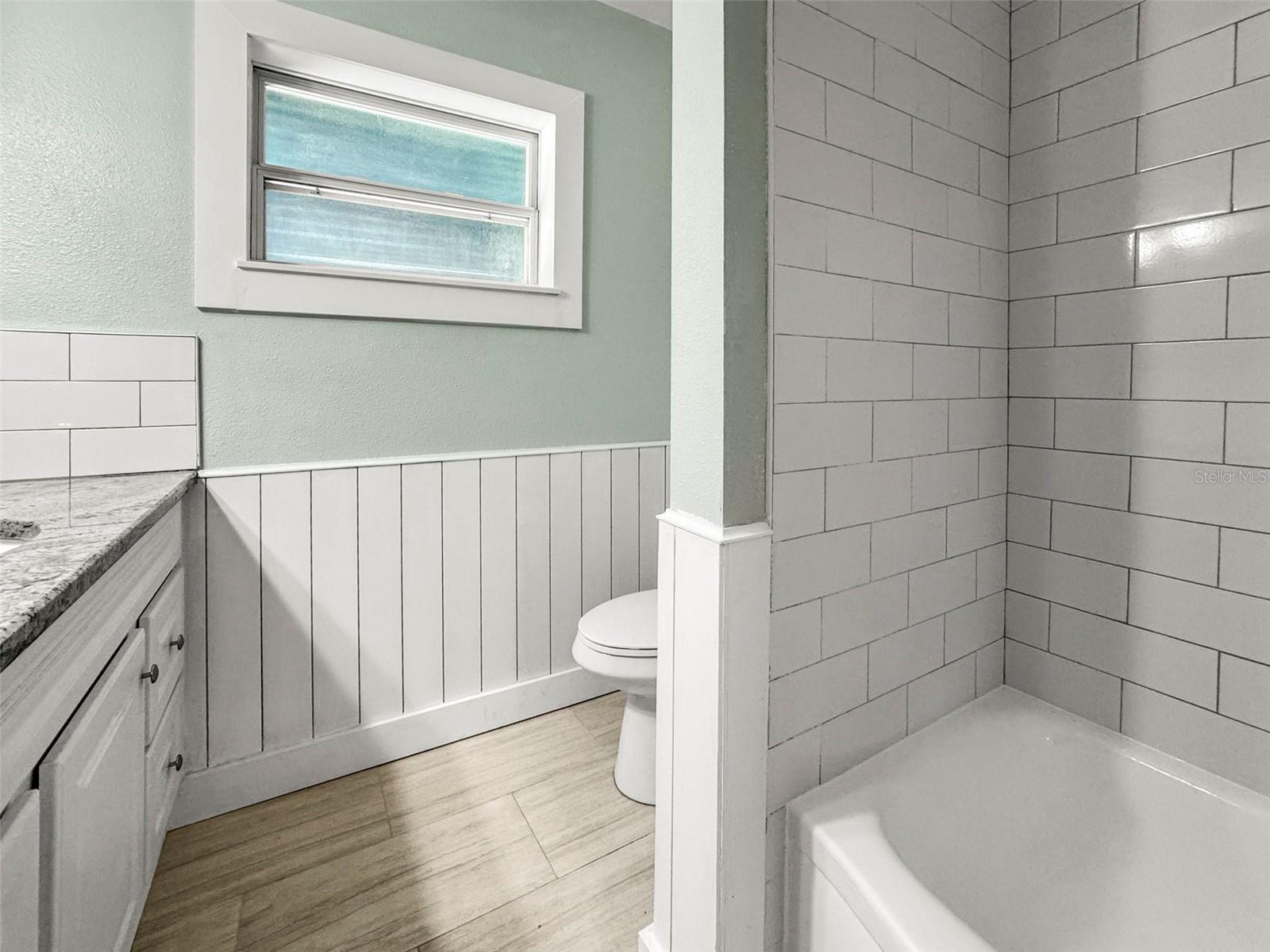 Updated bathroom with beadboard and shower/tub combo, new vanity and flooring
