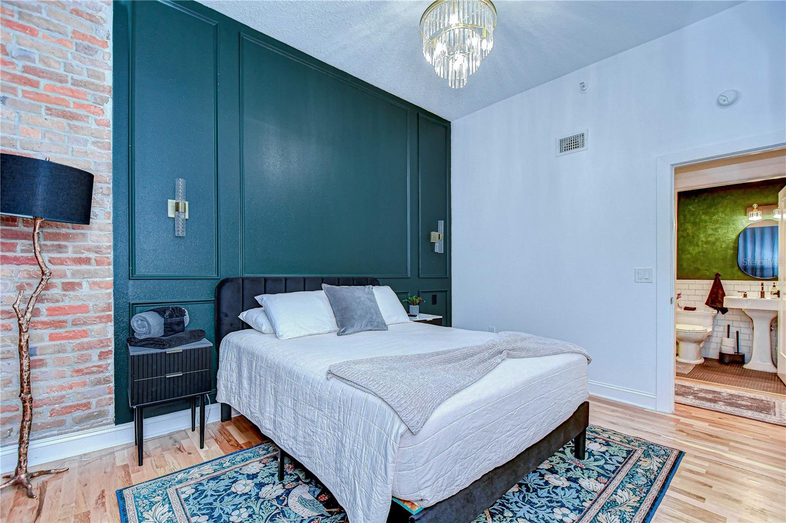 The bedroom features a chandelier and custom wall