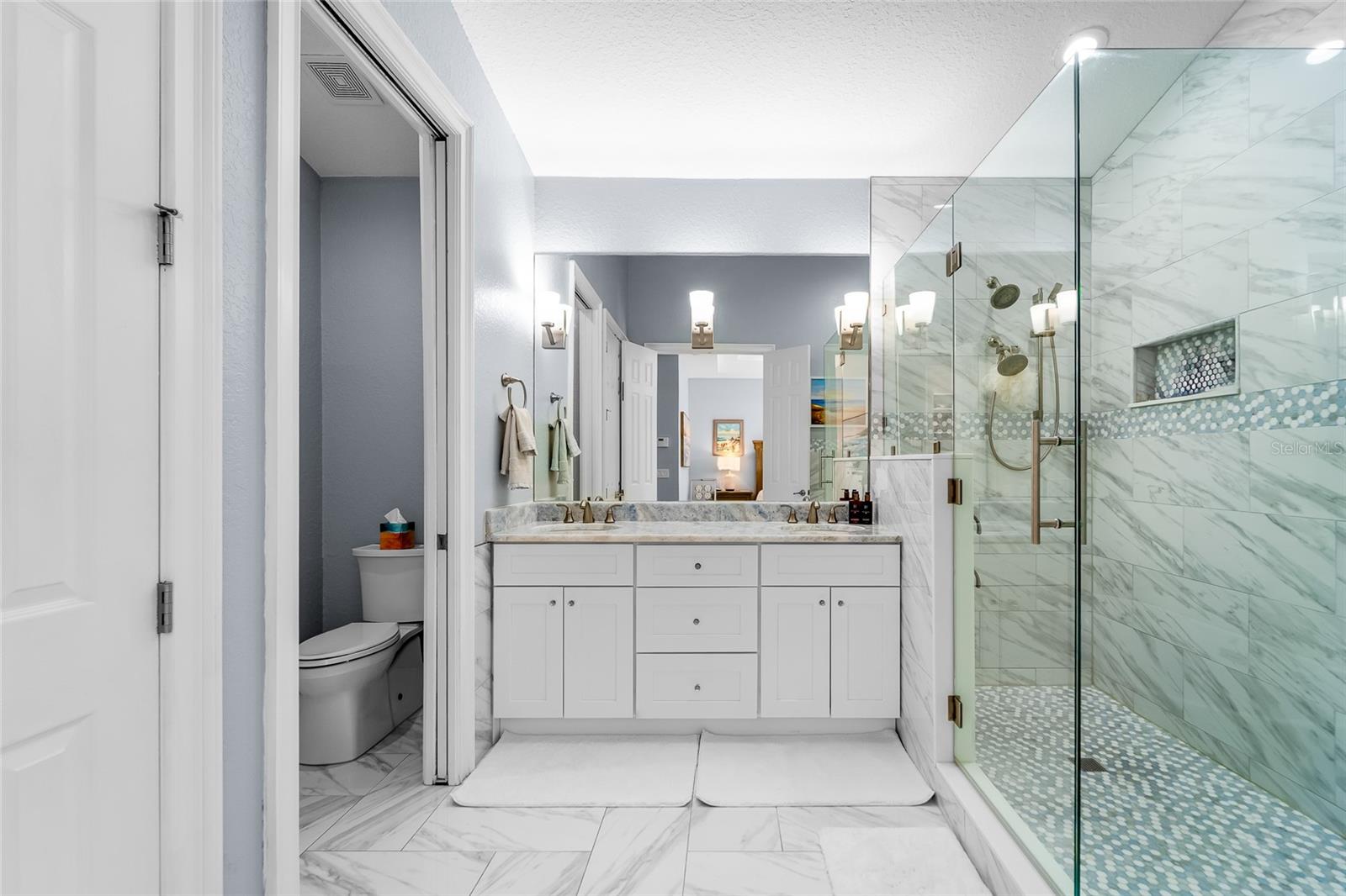 Primary bath with double sinks and pocket door to the water closet.