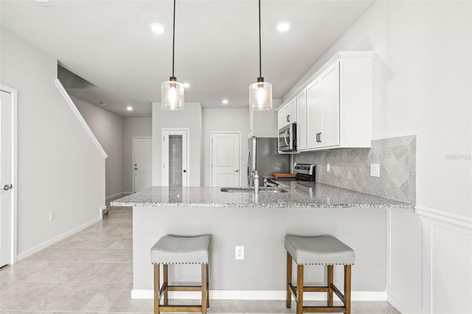 Above head lighting fixtures, tall cabinetry, glass door pantry.