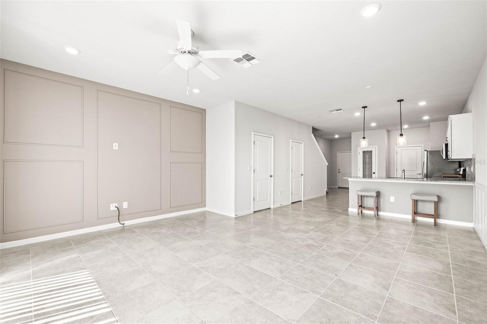 Living room area with accented wall looking toward the kitchen and dining area.