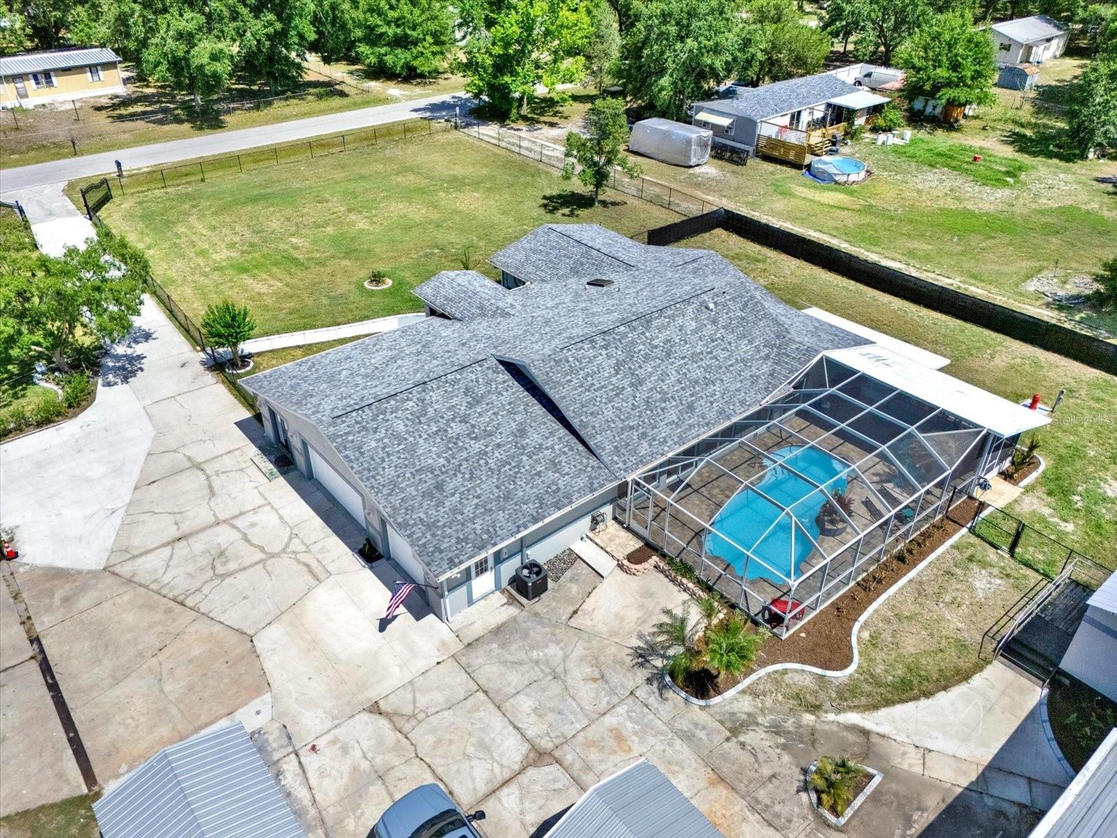 Aerial view of home with side loading garage and pool with screened lanai
