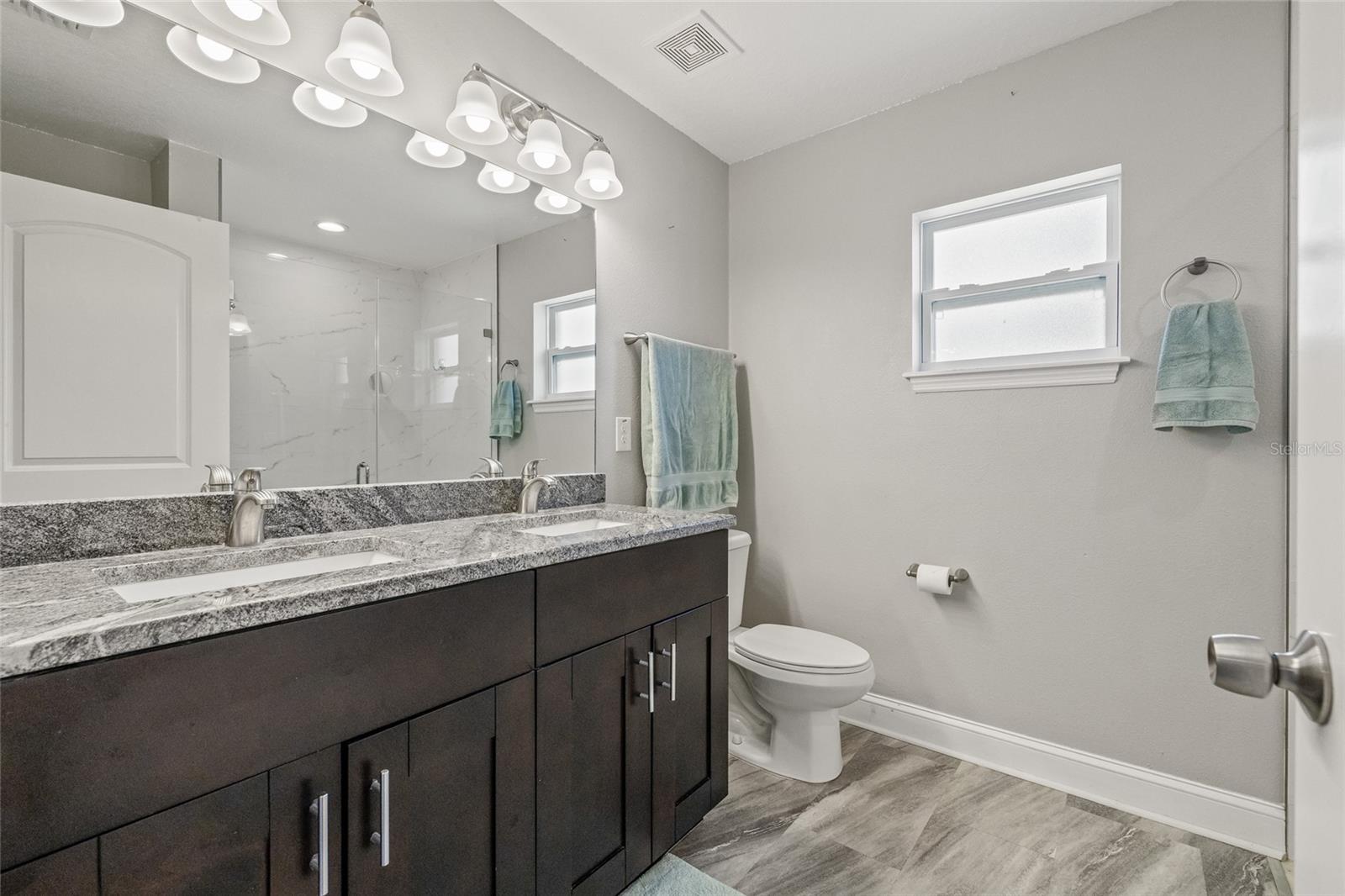 Dual sinks, granite counters, and stylish lighting make your morning routine a breeze in this thoughtfully designed primary bath.