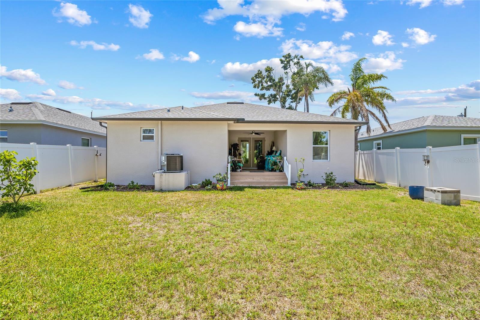 This back view highlights the spaciousness of the yard and the covered patio. Great layout for outdoor fun, gardening, or pets.