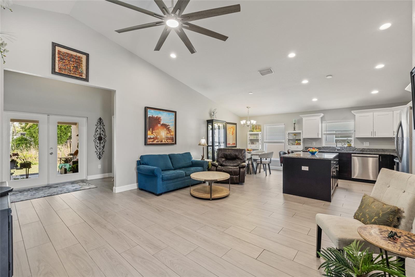 Wide-plank tile flooring and a soft neutral palette make this open-concept space feel even larger. French doors open to the backyard oasis, blending indoor comfort with outdoor charm.