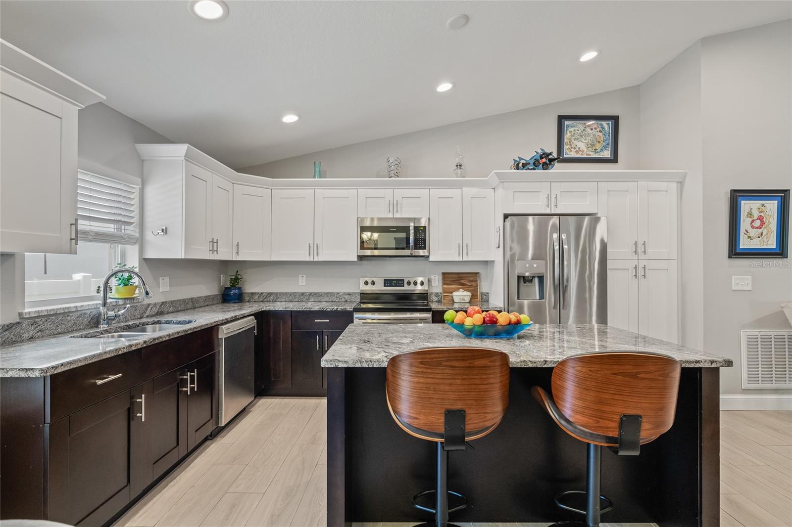 The heart of the home! This modern kitchen offers a perfect blend of white and espresso cabinetry, granite counters, and stainless steel Frigidaire appliances—plus a massive island with bar seating for two.