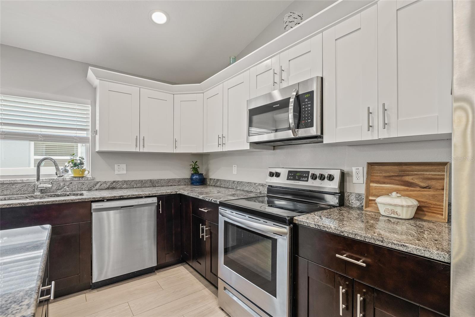Showcasing the microwave, smooth-top range, deep sink under a sunny window, and an abundance of sleek cabinetry—this space is as functional as it is beautiful.
