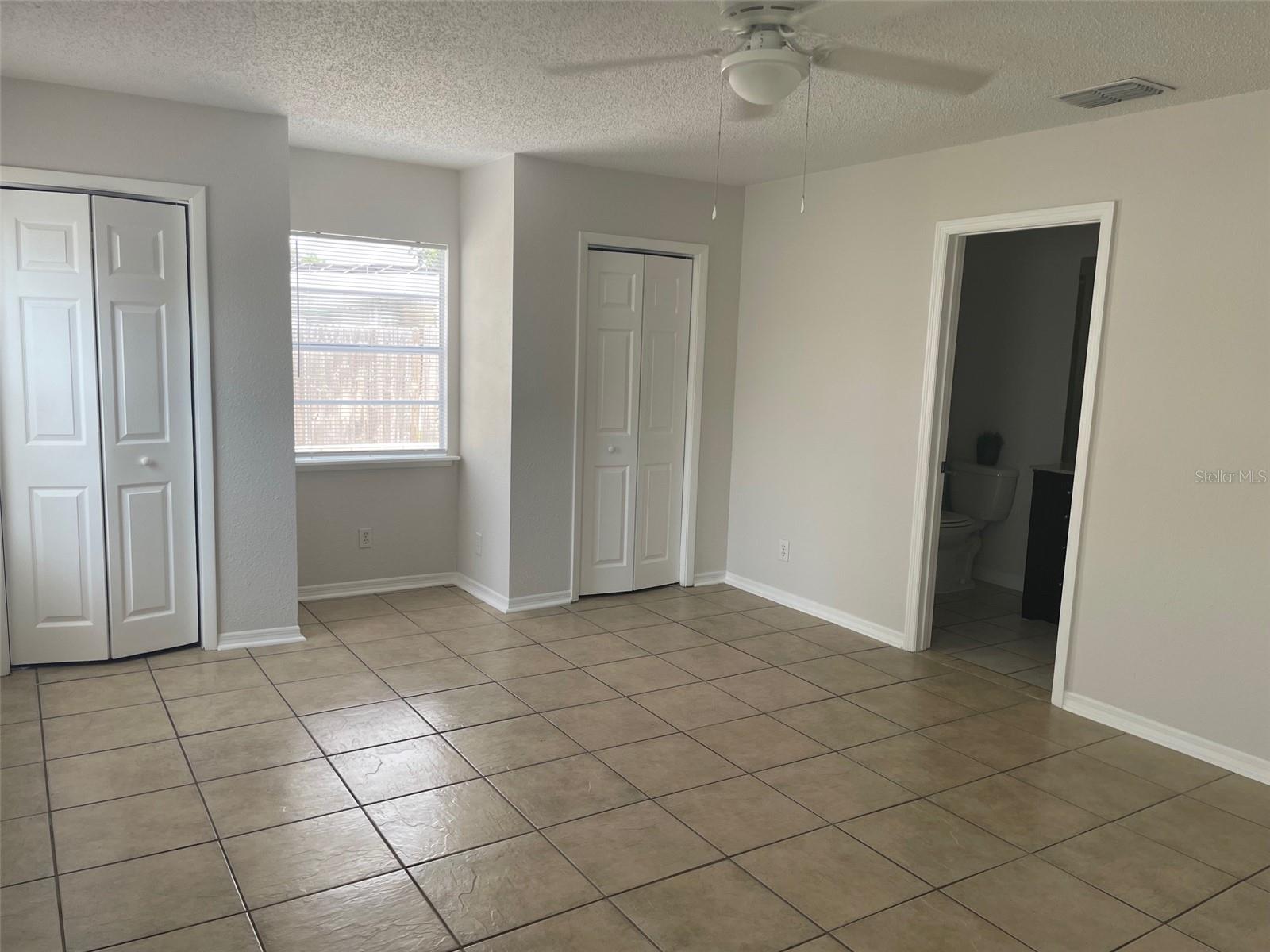 Primary bedroom open door on right leads to ensuite bath w/extra closet.