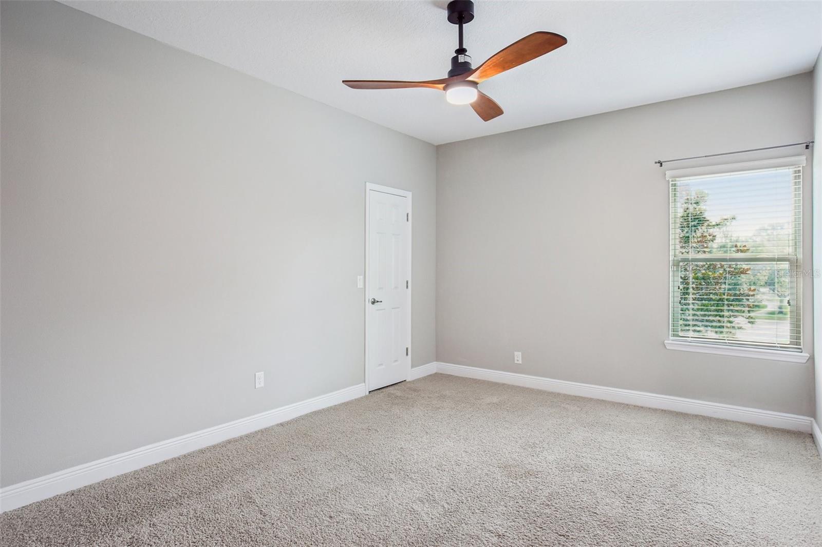 Bright carpeted bedroom with ceiling fan