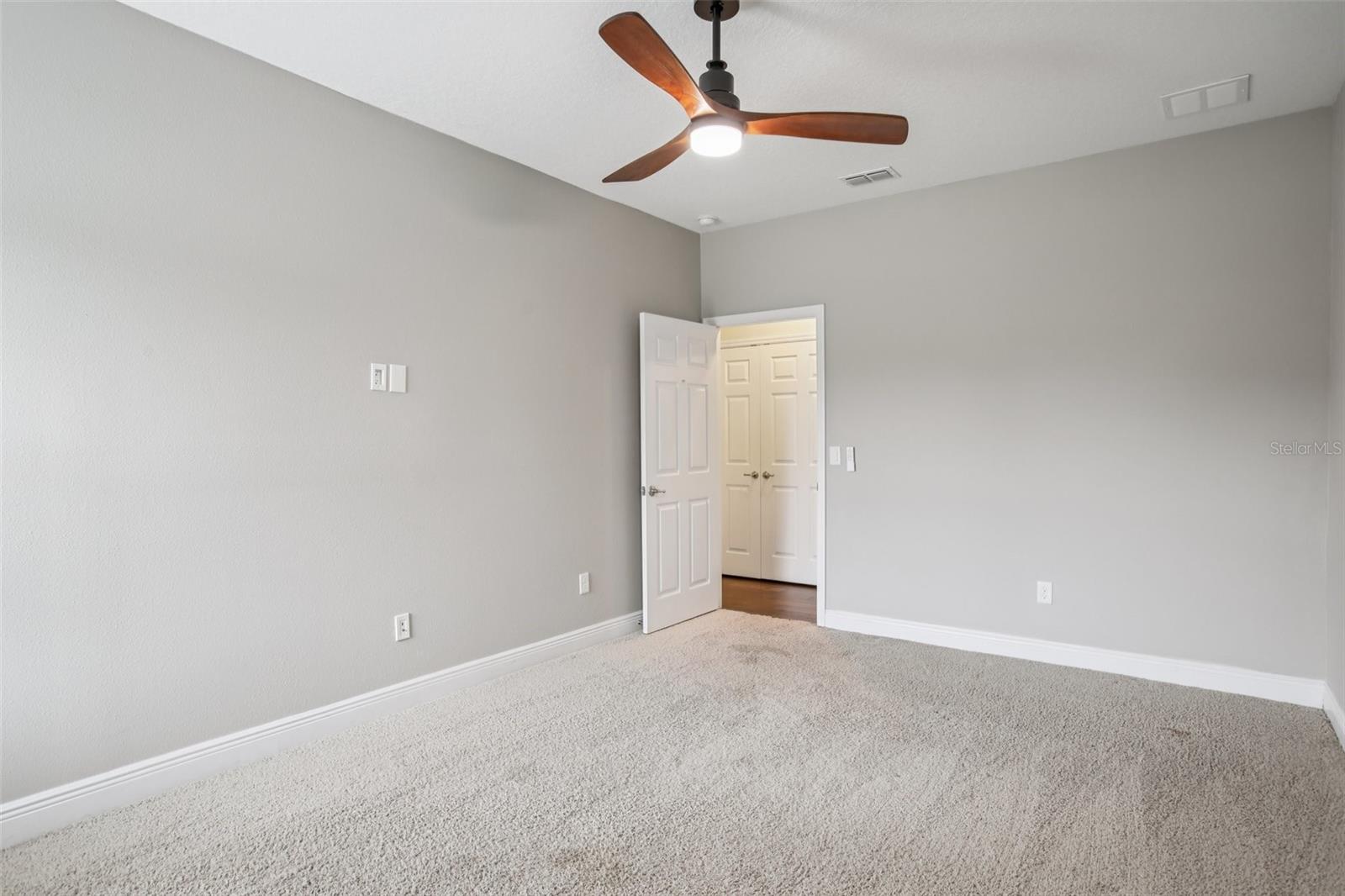 Spacious bedroom with neutral tones and ceiling fan