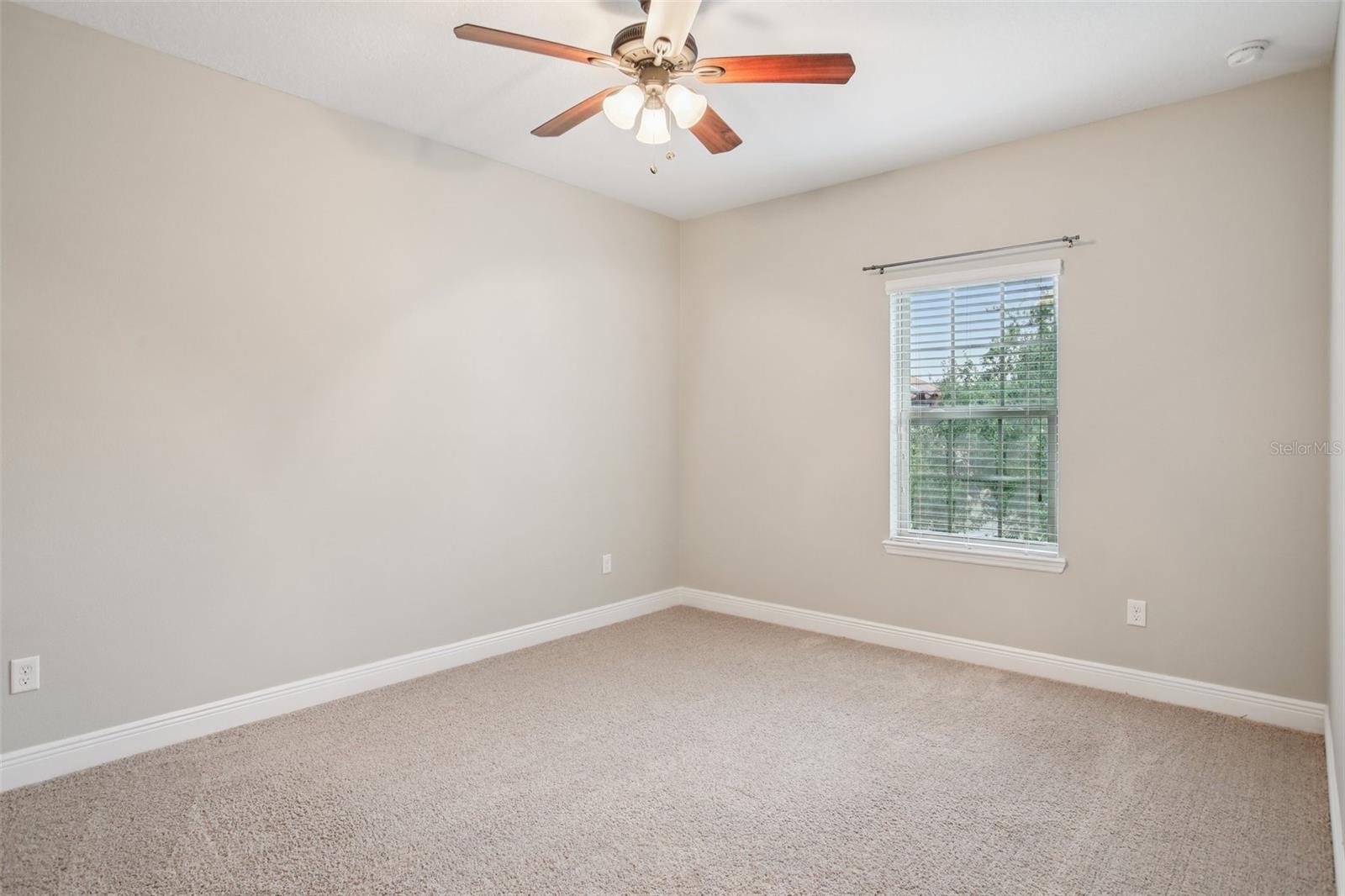 Bright carpeted bedroom with ceiling fan
