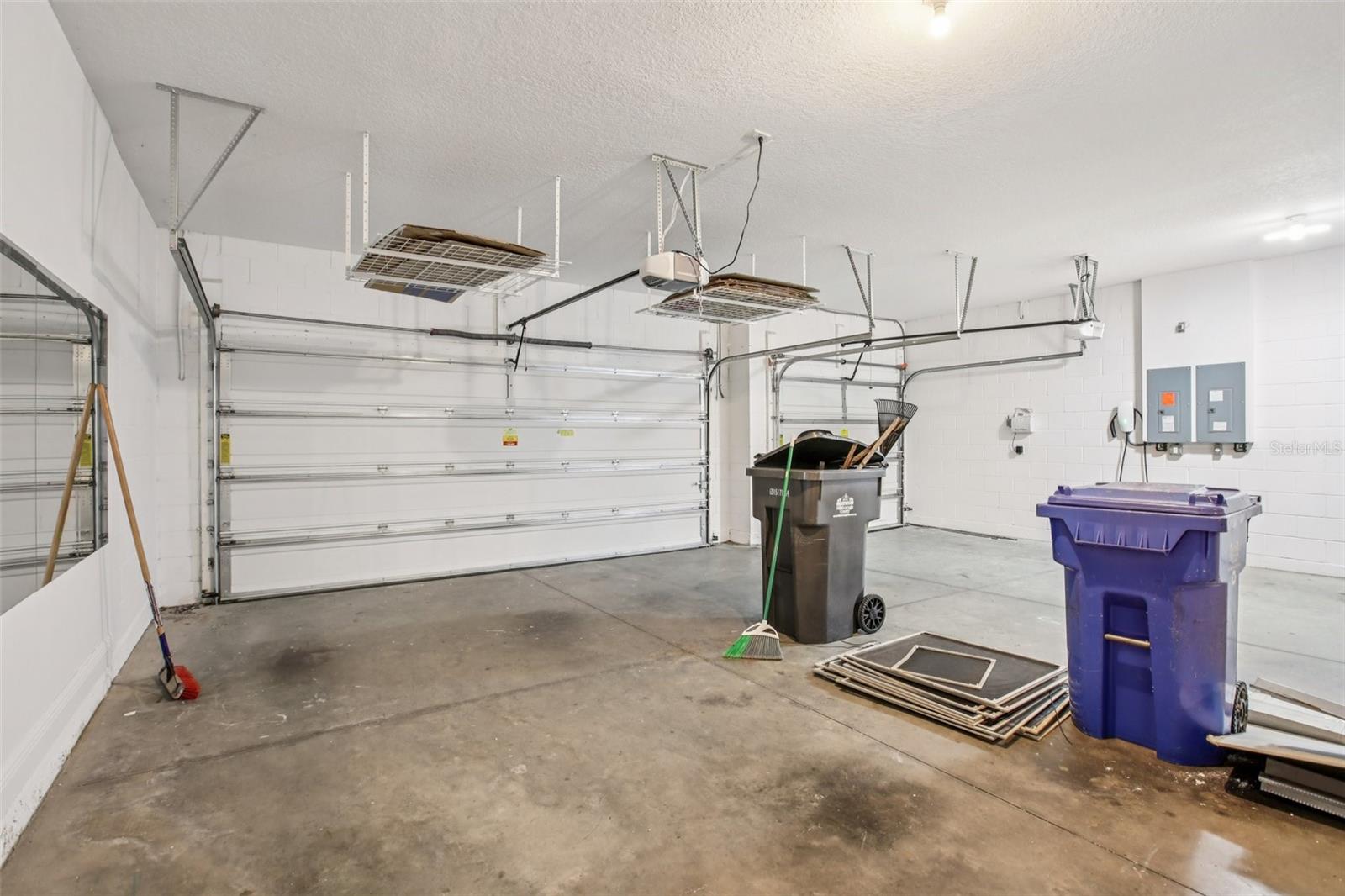 Spacious three-car garage with overhead storage racks and dual automatic doors.