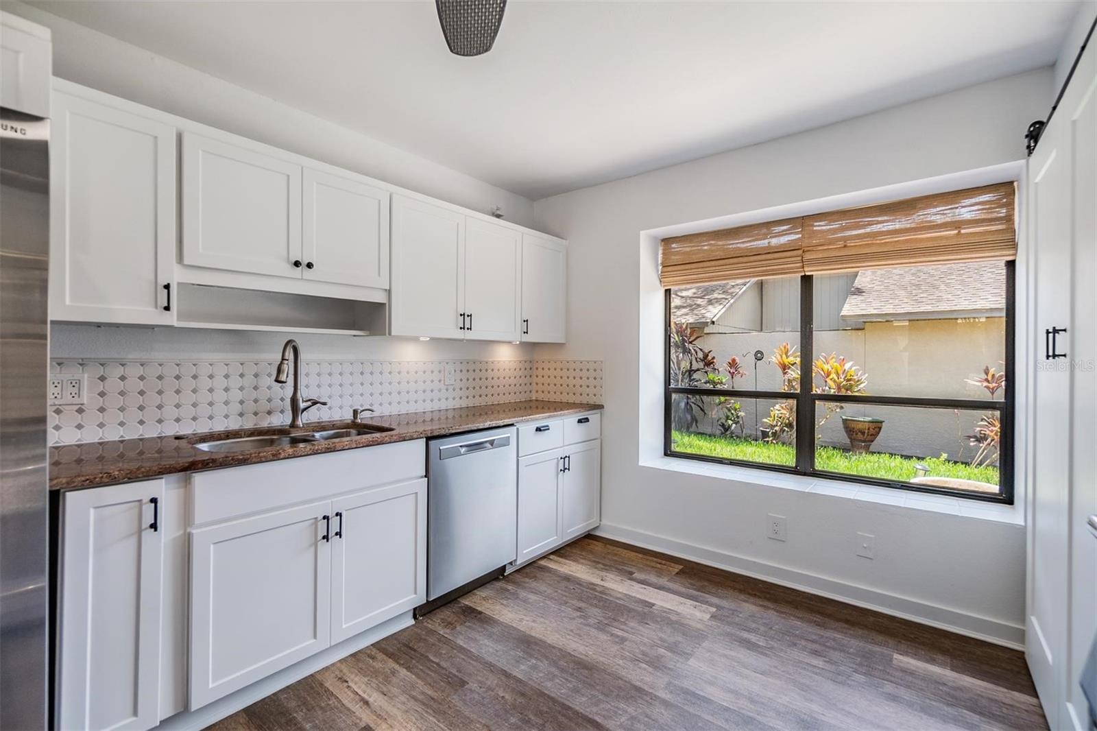 Updated kitchen with all stainless steel appliances, granite countertops, bright white modern cabinets, a pantry, and passthrough window to the dining room.
