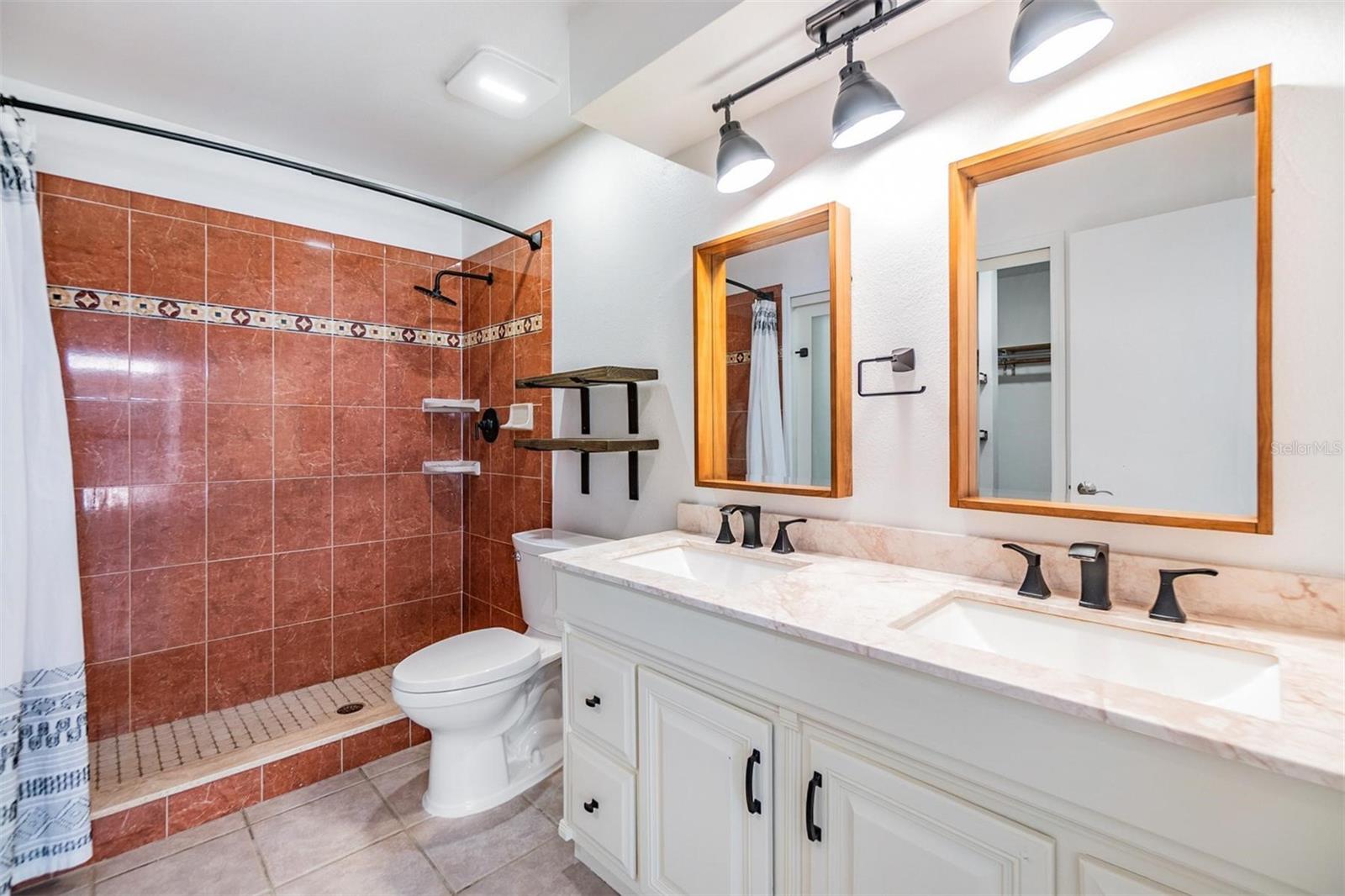 Primary ensuite bathroom with updated dual sink vanity, with granite countertop, and tile walk-in shower.