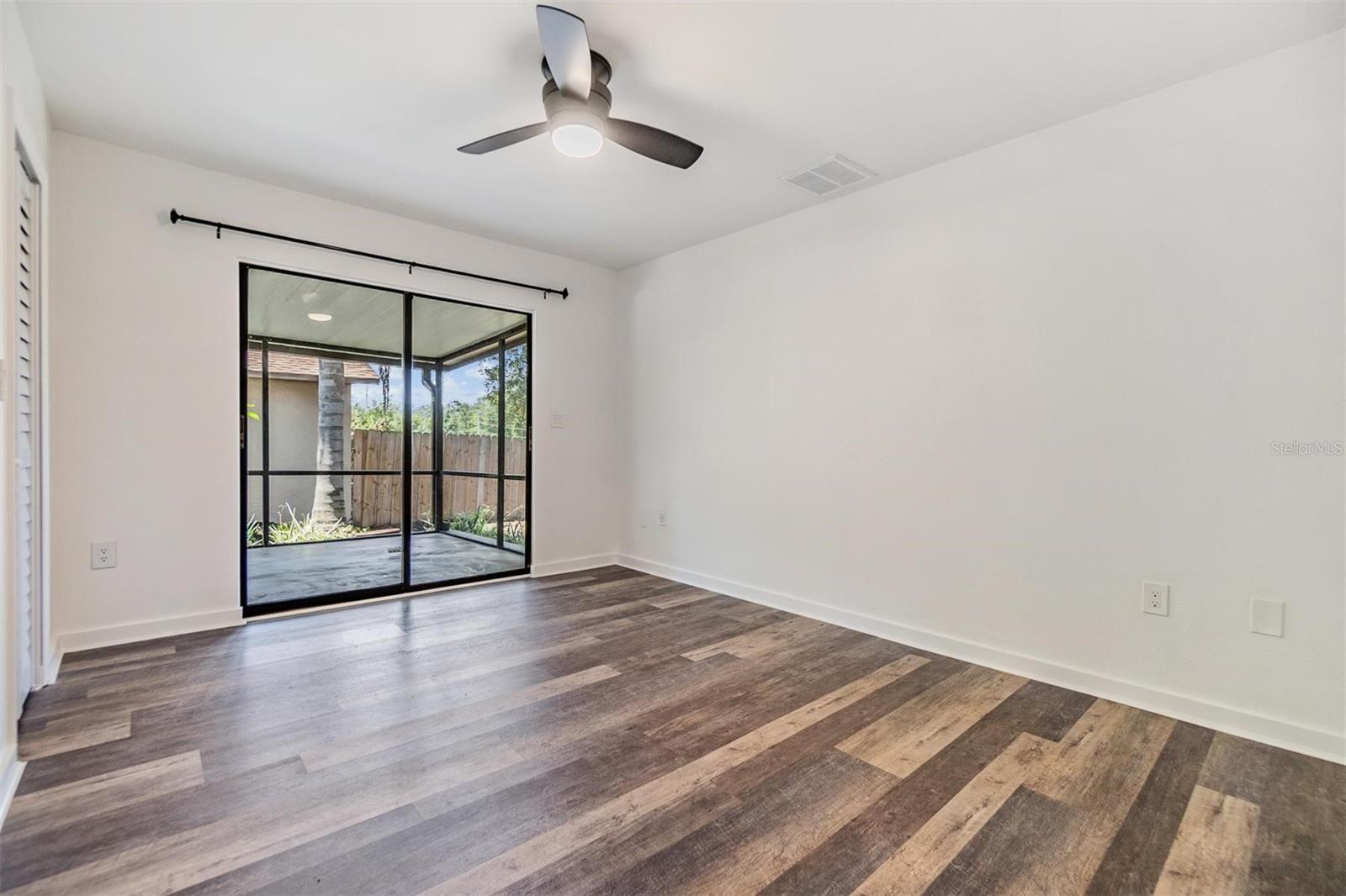 Second bedroom with glass sliders out to the screened-in patio and walk-closet.