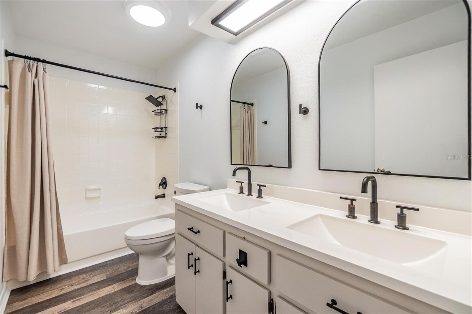 Second bathroom with dual sink vanity, and tub/shower combination.