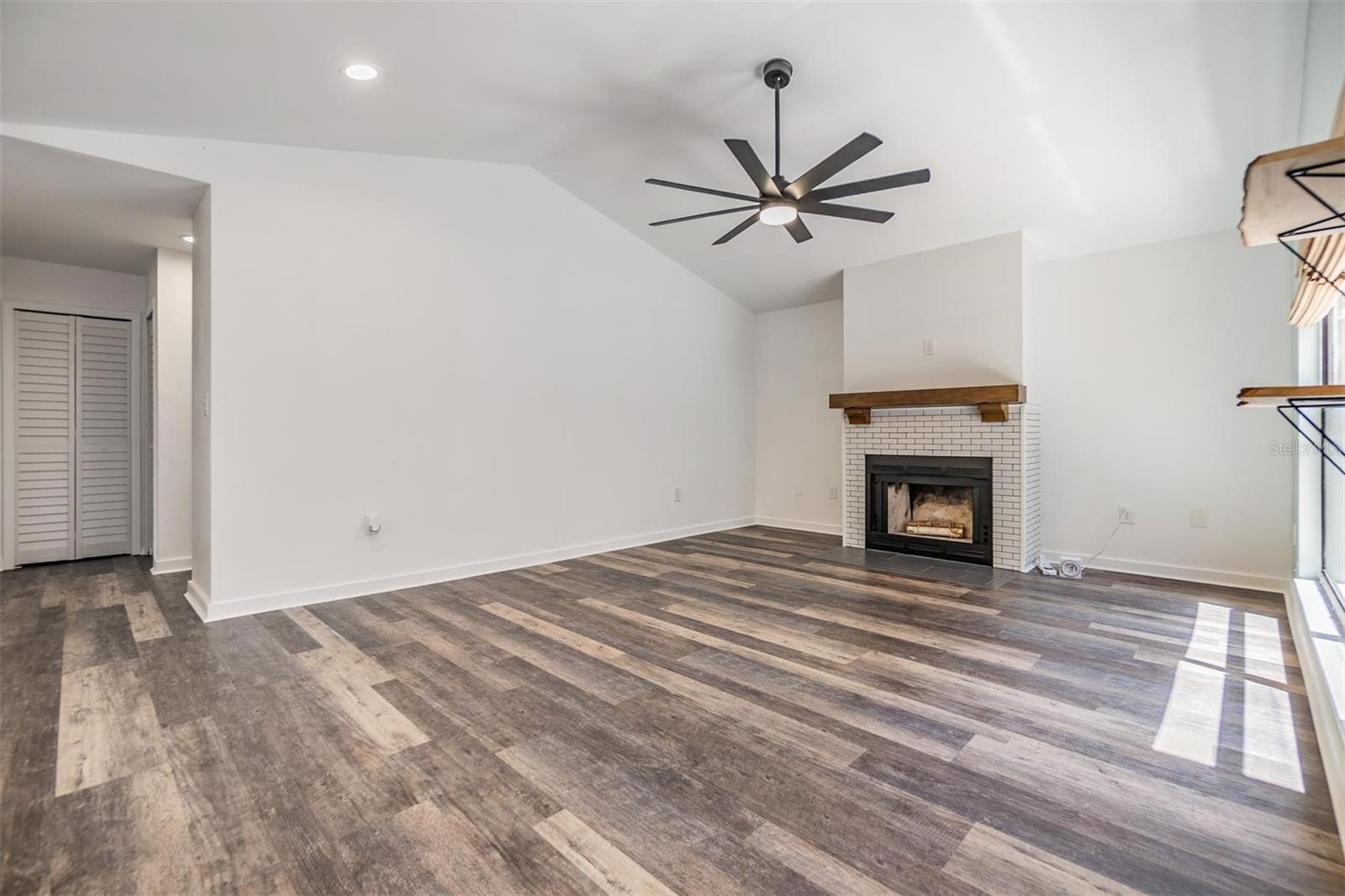 The living room features vaulted ceilings, a wood-burning fireplace for the cooler winter months, and views out to the atrium.
