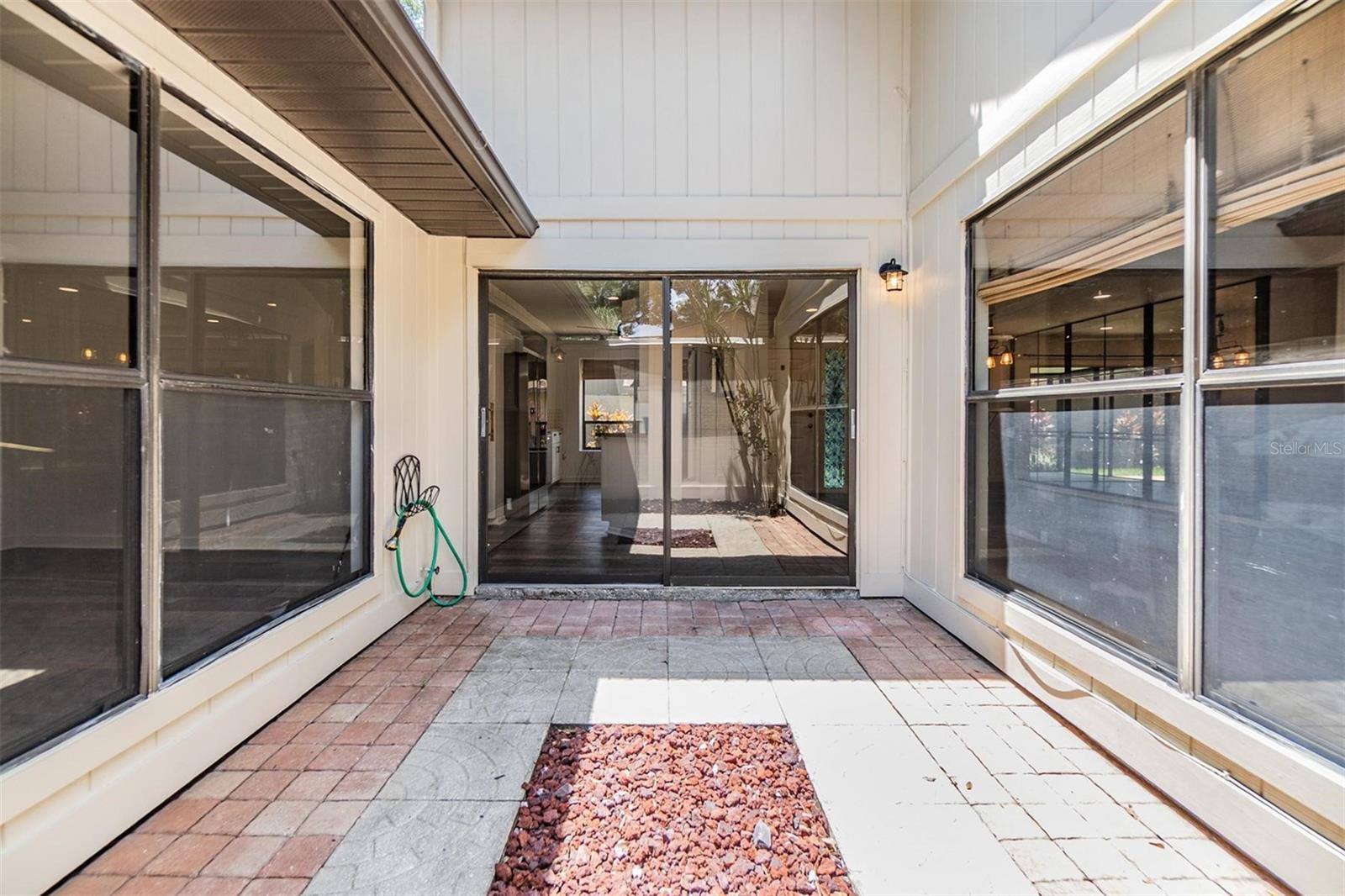 Atrium with glass slider access across from the kitchen and windows to bring natural lighting into the primary bedroom and living room.
