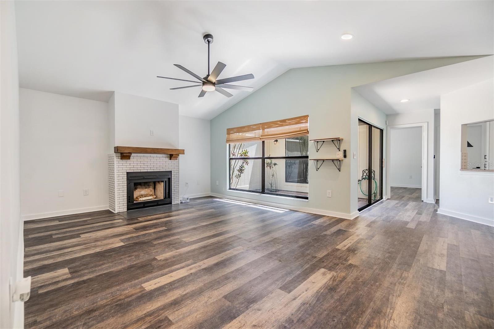 The living room features vaulted ceilings, a wood-burning fireplace for the cooler winter months, and views out to the atrium.