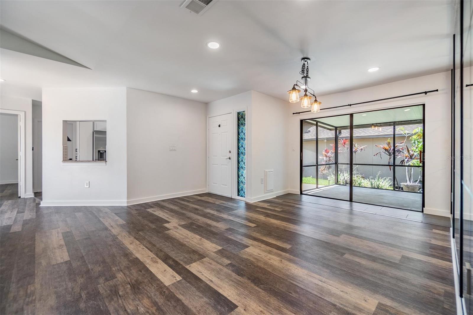 The dining room at the front of the home, front door with side light, and window pass through to the kitchen.