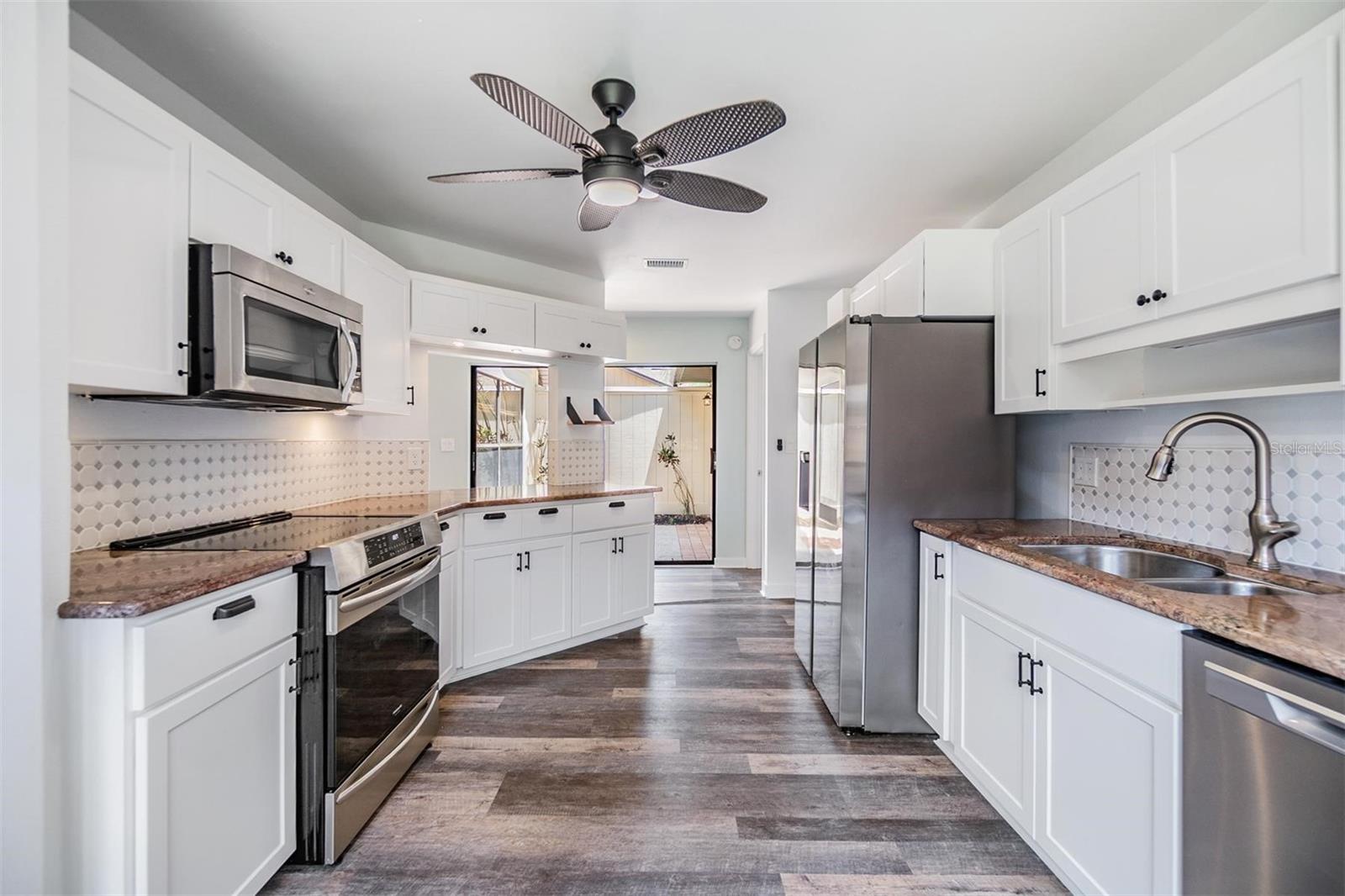 Updated kitchen with all stainless steel appliances, granite countertops, bright white modern cabinets, a pantry, and passthrough window to the dining room.