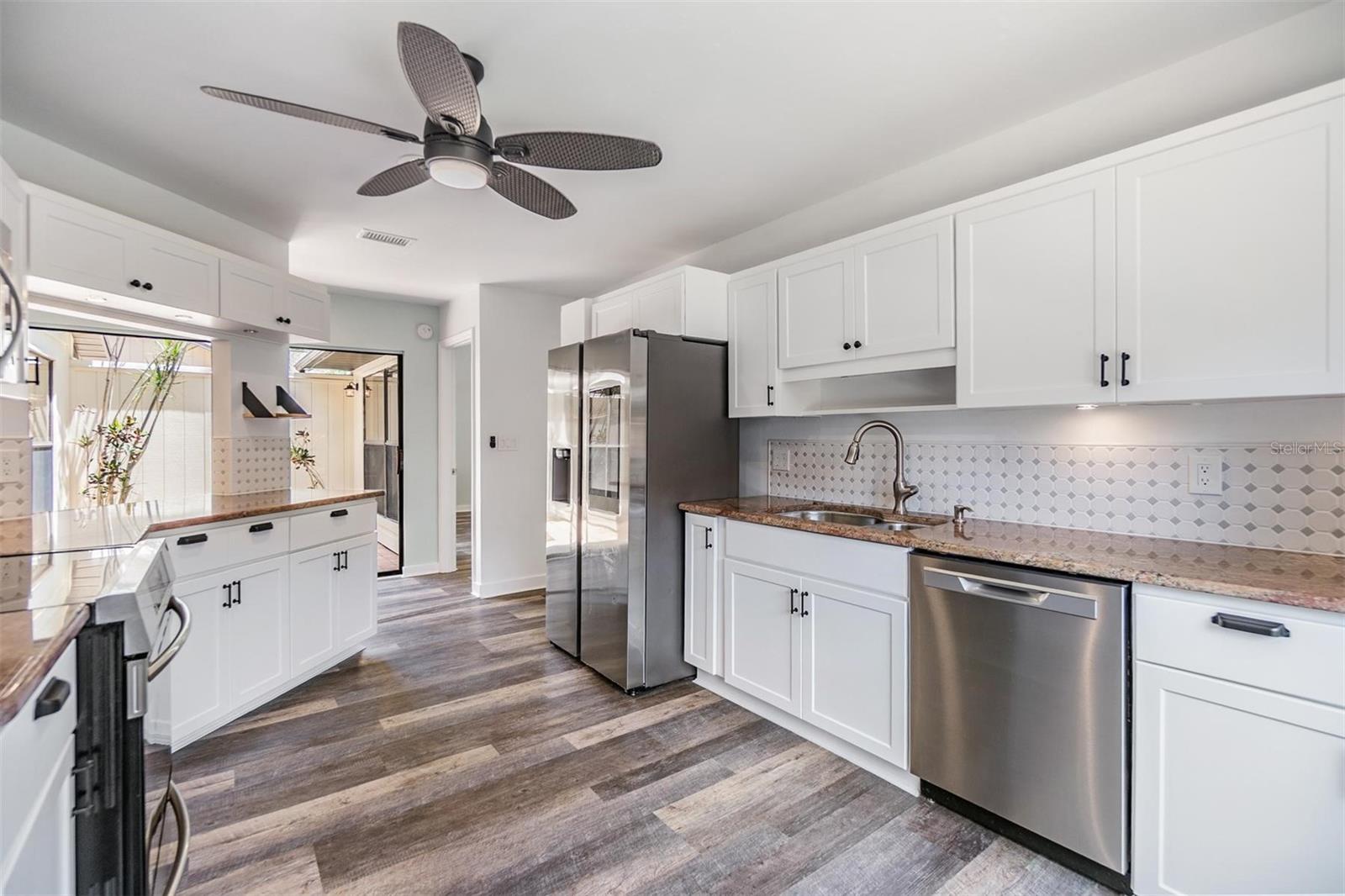 Updated kitchen with all stainless steel appliances, granite countertops, bright white modern cabinets, a pantry, and passthrough window to the dining room.