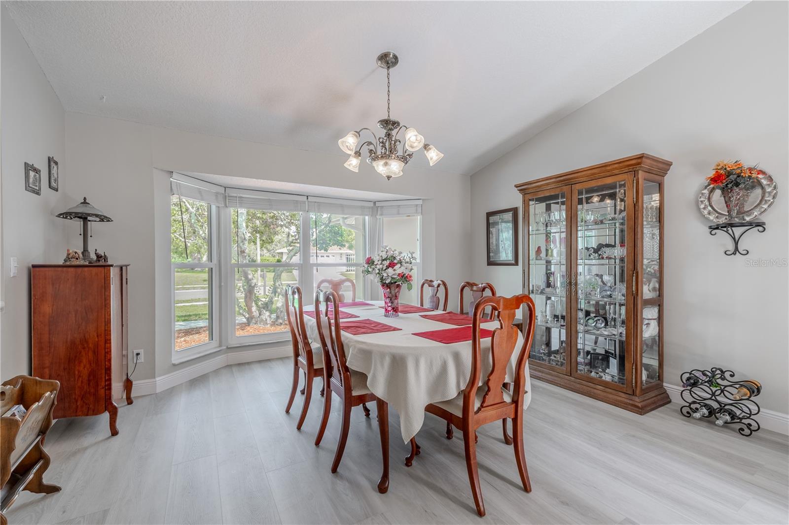 The formal dining room offers a warm and welcoming space, ideal for hosting holidays, dinner parties, or casual weeknight meals. A large bay window frames picturesque views of the front yard while allowing abundant natural light to fill the room. The freshly painted walls and new luxury vinyl plank flooring (2025) provide a modern, neutral backdrop that complements any décor style.