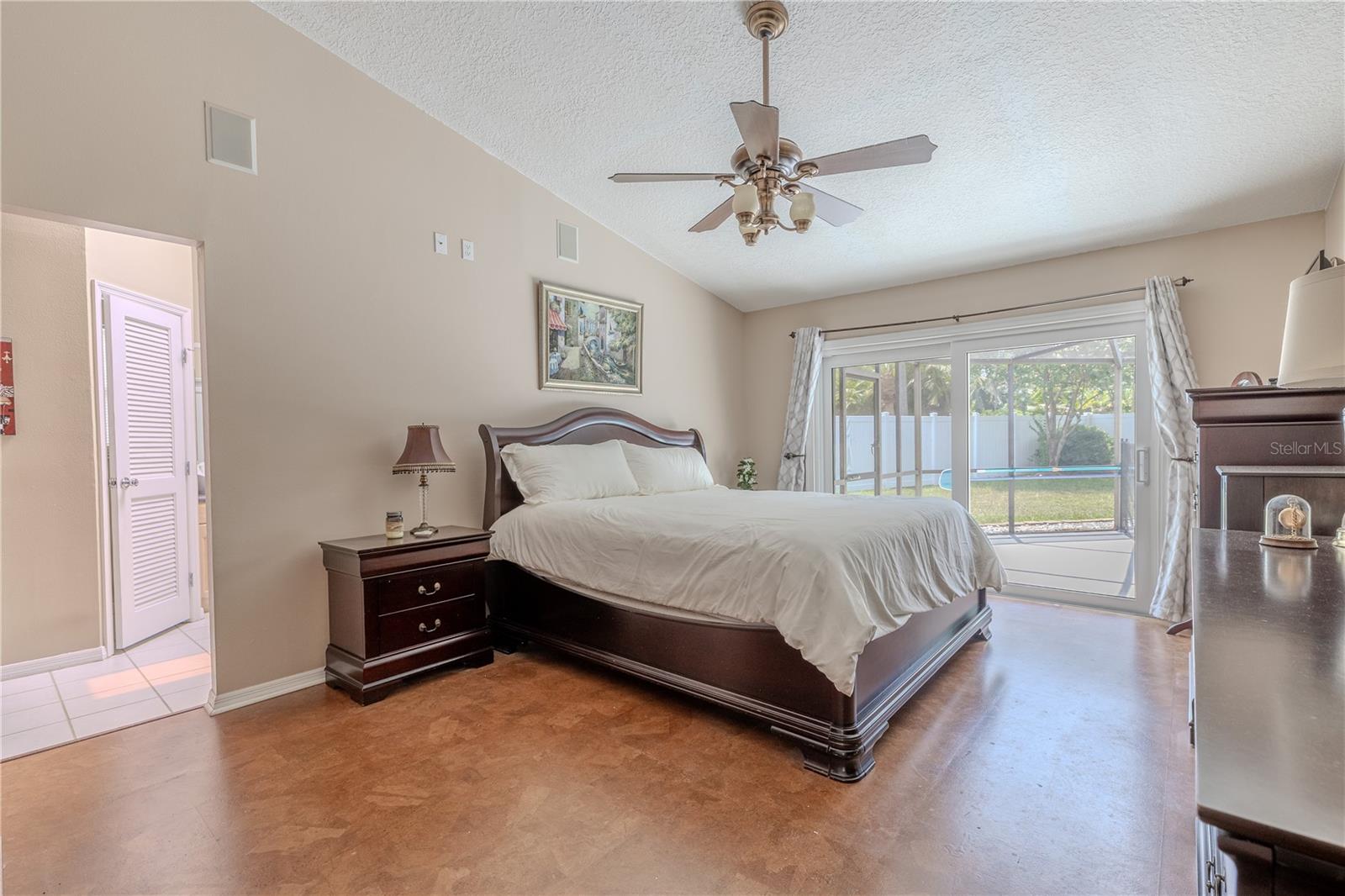 A ceiling fan with light fixture provides comfort year-round, while the generous layout easily accommodates a king-sized bed and full bedroom set. Beautiful cork flooring.Wake up to views of the pool and step directly outside to enjoy a morning coffee under the lanai—this primary suite offers both privacy and convenience with a direct connection to your outdoor oasis.