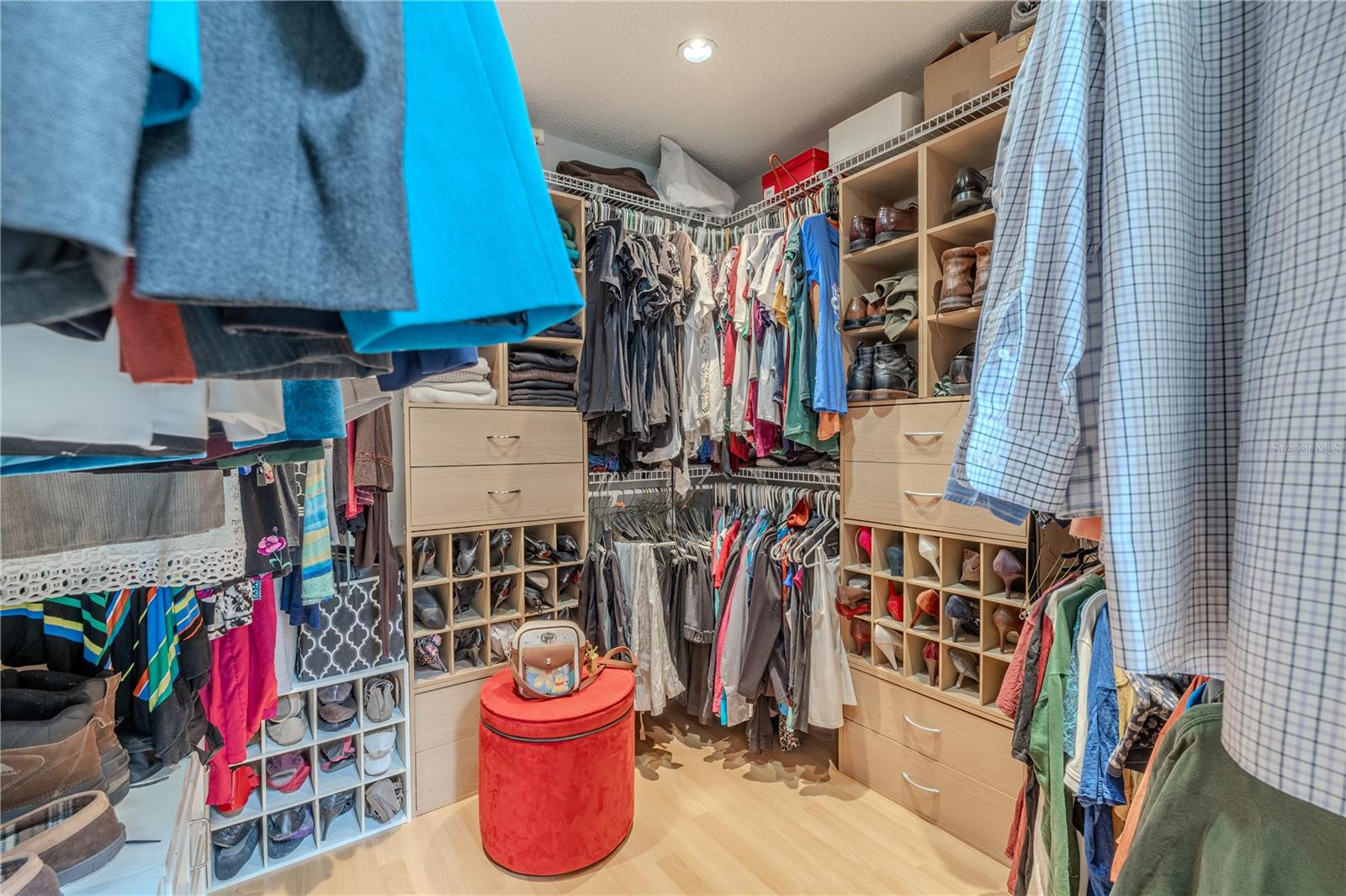 The primary walk-in closet is impressively designed with functionality and organization in mind. Custom built-ins offer a place for everything, including multiple hanging rods, open shelving, and generous drawer storage. Dedicated shoe cubbies and accessory compartments provide tailored storage solutions to keep everything neat and within easy reach.Spacious enough for two, this well-lit walk-in closet makes staying organized effortless and adds an element of luxury to everyday living.
