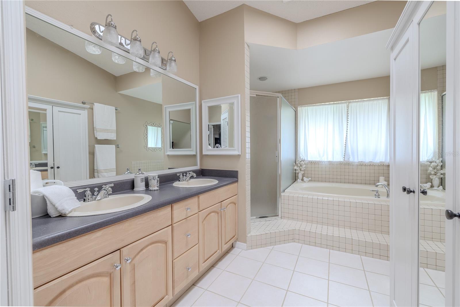 A large double vanity with updated lighting and expansive mirror provides ample storage and counter space, perfect for busy mornings.